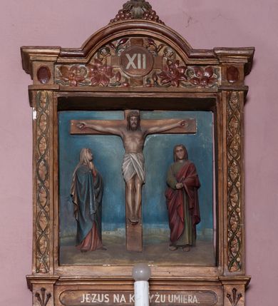 Zdjęcie nr 4: Stacje Drogi krzyżowej w kształcie stojących prostokątów zostały ujęte architektoniczną ramą. Obrazy ustawiono na cokole, po bokach są flankowane dwoma pilastrami, podtrzymującymi wyłamane belkowanie, zamknięte gzymsem w kształcie łuku nadwieszonego. Na szczycie, w rzeźbionych owocach winogron osadzono grecki krzyżyk o trójlistnie zakończonych ramionach z uskokami. Pilastry są zdobione symetryczną wicią cierniową, a pole zwieńczenia bogato dekorowane wicią roślinną złożoną z bujnych, czerwonych kwiatów otaczających numer stacji umieszczony w owalu na tle krzyżyka greckiego. 
Sceny przeważnie wielopostaciowe, płaskorzeźbione, barwnie polichromowane. Postacie o poprawnej anatomii ciała, poruszone, na pierwszym planie bardziej wypukłe. Tło błękitne, malowane. W partii cokołu umieszczono malowane tytuły stacji:
I. „JEZUS NA ŚMIERĆ OSĄDZONY.”
II. „JEZUS BIERZE KRZYŻ NA RAMIONA.”
III. „JEZUS PIERWSZY RAZ UPADA.”
IV. „JEZUS SPOTYKA NAJŚW(IĘTSZĄ) MATKĘ SWOJĄ”
V. „SZYMON CYR(ENEJCZYK) POMAGA NIEŚĆ KRZYŻ JEZUSA”
VI. „ŚW(IĘTA) WERONIKA OCIERA TWARZ JEZUSA”
VII. „JEZUS DRUGI RAZ UPADA”
VIII. „JEZUS NAPOTYKA PŁACZĄCE NIEWIASTY”
IX. „JEZUS TRZECI RAZ UPADA.”
X. „JEZUS Z SZAT OBNAŻONY”
XI. „JEZUS DO KRZYŻA PRZYBITY”
XII. „JEZUS NA KRZYŻU UMIERA.”
XIII. „JEZUS Z KRZYŻA ZDJĘTY.”
XIV. „JEZUS DO GROBU ZŁOŻONY.”
