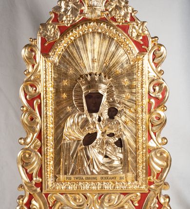 Zdjęcie nr 2: Feretron dwustronny, umieszczony na dwóch nóżkach, ustawionych na niskich cokołach. W centralnej części obrazy w kształcie stojącego prostokąta, zamkniętego łukiem nadwieszonym: po jednej stronie Matki Boskiej Częstochowskiej, po drugiej św. Józefa. Obrazy otoczone bogato dekorowaną ramą, oplecioną stylizowanym ornamentem z liści akantu, w zwieńczeniu winne grona i kłosy zbóż. U szczytu mały łaciński krzyżyk. Obraz Marii w typie Matki Boskiej Częstochowskiej. Na postacie  i tło nałożone złocone sukienki. Poniżej banderola z napisem „POD TWOJĄ OBRONĘ UCIEKAMY SIĘ”. Na obrazie ze św. Józefem święty ukazany frontalnie, z Dzieciątkiem Jezus na lewym ramieniu. Pociągłą twarz okala ciemna broda i wąsy. W prawej ręce święty trzyma lilię. Dzieciątko Jezus zwrócone jest w trzech czwartych w prawo, lewą rękę wyciąga w stronę św. Józefa. Na postacie Marii i Dzieciątka nałożone złocone sukienki i nimby. Tło złocone. 
