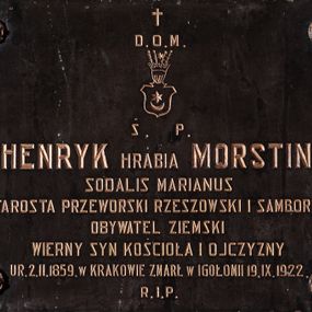 Zdjęcie nr 1: Tablica epitafijna w kształcie leżącego prostokąta, przymocowana do ściany czterema nitami, z zewnątrz ozdobionymi rozetkami. W polu złocona, kuta inskrypcja „D(EO) O(PTIMO) M(AXIMO) / Ś(WIĘTEJ) P(AMIĘCI) / HENRYK HRABIA MORSTIN / SODALIS MARIANUS / STAROSTA PRZEWORSKI RZESZOWSKI I SAMBORSKI / OBYWATEL ZIEMSKI / WIERNY SYN KOŚCIOŁA I OJCZYZNY / UR(ODZONY) 2. II. 1859. W KRAKOWIE ZMARŁ W IGOŁOMII 19. IX. 1922. / R(EQUIESCAT) I(N) P(ACE)”. Między pierwszym a drugim wierszem inskrypcji, kuty i złocony herb Leliwa. W tarczy o ściętych narożach głowicy i podstawie z języczkiem umieszczono godło herbu Leliwa: księżyc, a nad nim gwiazda. Na tarczy hełm z otwartą koroną i klejnotem w postaci czterech piór, na których położono gwiazdę.