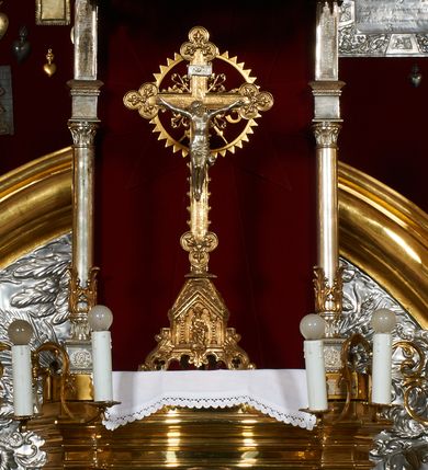Zdjęcie nr 1: Tabernakulum w formie skrzynki, na cokole, z wybrzuszonym licem, z korpusem flankowanym ustawionymi ukośnie pilastrami, dźwigającymi gzyms, o trzonach przechodzących dołem w spływy wolutowe dekorowane motywami rocaille. Drzwiczki kwadratowe, zamknięte od góry półkoliście, ujęte ramą dekorowaną ornamentem roślinnym, w polu aplikowany kielich eucharystyczny w otoczeniu kłosów zbóż i kiści winogron. Na tabernakulum tron wystawienia utworzony ze ścianki wyłożonej czerwonym atłasem flankowanej kolumienkami dekorowanymi liśćmi akantu, ustawionymi na postumentach i dźwigającymi podwójne imposty i stojące na nich wazoniki. Całość zwieńczona baldachimem w formie kopuły zakończonej krzyżem, na planie analogicznym do tabernakulum, z podwieszonym stylizowanym lambrekinem. Drewniana struktura tabernakulum pozłacana, tron posrebrzany i pozłacany.

