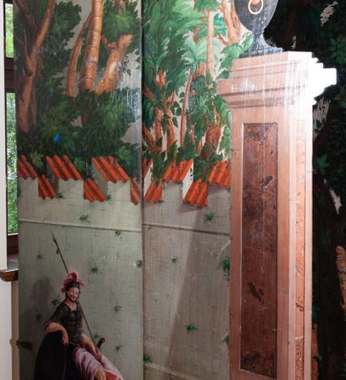 Zdjęcie nr 15: Oprawa grobu Pańskiego kulisowa, pięciopłaszczyznowa. Pierwszy plan tworzy iluzjonistyczna dekoracja, utworzona z bramy składającej się z dwóch filarów zwieńczonych wazonami z antabami oraz muru z krenelażem. Na tle muru ukazani dwaj rzymscy legioniści, po lewej stronie siedzący, po prawej stojący. W tle bogata roślinność egzotyczna z palmami. Na pozostałych planach namalowana roślinność leśna z egzotycznymi gatunkami palm. Na trzeciej parze kulis  przedstawieni dwaj rzymscy legioniści, lewy w pozycji stojącej, prawy leżącej, z głową wspartą na ręce. Wszystkie cztery płaszczyzny zamknięte łukami z namalowanym błękitnym niebem z gwiazdami, ujętym obłokami. 
Na ścianie zamykającej dekorację ukazano kamienny grób, po bokach którego siedzi i leży po trzech legionistów rzymskich z każdej strony. Nad nimi namalowane zalesione wzgórze Golgoty z trzema krzyżami, przed którymi stoi płaczący anioł. W tle widoczny jest pejzaż Jerozolimy, nad którym ukazano zaćmione słońce. W górnej części ściany ukazano niebo z nałożonym medalionem utworzonym z obłoków, z dwiema uskrzydlonymi główkami anielskimi, w glorii promienistej. 



