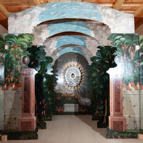 Zdjęcie nr 1: Oprawa grobu Pańskiego kulisowa, pięciopłaszczyznowa. Pierwszy plan tworzy iluzjonistyczna dekoracja, utworzona z bramy składającej się z dwóch filarów zwieńczonych wazonami z antabami oraz muru z krenelażem. Na tle muru ukazani dwaj rzymscy legioniści, po lewej stronie siedzący, po prawej stojący. W tle bogata roślinność egzotyczna z palmami. Na pozostałych planach namalowana roślinność leśna z egzotycznymi gatunkami palm. Na trzeciej parze kulis  przedstawieni dwaj rzymscy legioniści, lewy w pozycji stojącej, prawy leżącej, z głową wspartą na ręce. Wszystkie cztery płaszczyzny zamknięte łukami z namalowanym błękitnym niebem z gwiazdami, ujętym obłokami. 
Na ścianie zamykającej dekorację ukazano kamienny grób, po bokach którego siedzi i leży po trzech legionistów rzymskich z każdej strony. Nad nimi namalowane zalesione wzgórze Golgoty z trzema krzyżami, przed którymi stoi płaczący anioł. W tle widoczny jest pejzaż Jerozolimy, nad którym ukazano zaćmione słońce. W górnej części ściany ukazano niebo z nałożonym medalionem utworzonym z obłoków, z dwiema uskrzydlonymi główkami anielskimi, w glorii promienistej. 




