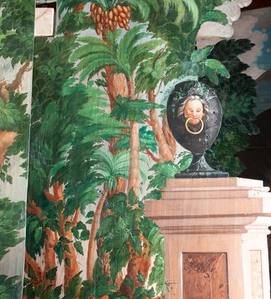 Zdjęcie nr 19: Oprawa grobu Pańskiego kulisowa, pięciopłaszczyznowa. Pierwszy plan tworzy iluzjonistyczna dekoracja, utworzona z bramy składającej się z dwóch filarów zwieńczonych wazonami z antabami oraz muru z krenelażem. Na tle muru ukazani dwaj rzymscy legioniści, po lewej stronie siedzący, po prawej stojący. W tle bogata roślinność egzotyczna z palmami. Na pozostałych planach namalowana roślinność leśna z egzotycznymi gatunkami palm. Na trzeciej parze kulis  przedstawieni dwaj rzymscy legioniści, lewy w pozycji stojącej, prawy leżącej, z głową wspartą na ręce. Wszystkie cztery płaszczyzny zamknięte łukami z namalowanym błękitnym niebem z gwiazdami, ujętym obłokami. 
Na ścianie zamykającej dekorację ukazano kamienny grób, po bokach którego siedzi i leży po trzech legionistów rzymskich z każdej strony. Nad nimi namalowane zalesione wzgórze Golgoty z trzema krzyżami, przed którymi stoi płaczący anioł. W tle widoczny jest pejzaż Jerozolimy, nad którym ukazano zaćmione słońce. W górnej części ściany ukazano niebo z nałożonym medalionem utworzonym z obłoków, z dwiema uskrzydlonymi główkami anielskimi, w glorii promienistej. 



