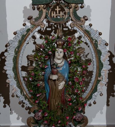 Zdjęcie nr 1: Na postumencie o kształcie wolutowym zaopatrzonym w otwory na drążki do noszenia, przyozdobionym żłobkowaniem, wolutami w narożach oraz po jednej róży na bokach umieszczona została dwustronnie rzeźbiona, żłobkowana, owalna rama, przyozdobiona kulkami zawieszonymi na metalowych uchwytach, zwieńczona dwiema wolutami z różyczką na jednym końcu podtrzymującymi monogram IHS w wieńcu laurowym z dwiema wiszącymi kulkami, powyżej dwiema półwolutami przyozdobionymi wiszącymi kulkami i przytrzymującymi czerwoną koronę w typie zamkniętym z krzyżykiem równoramiennym, w zwieńczeniu dwa wolutowe kabłąki, na nich rozeta. 
Dekoracja malarska feretronu w kolorze zielonym, brązowym, białym i złotym.
Figura Matki Bożej w glorii promienistej. Matka Boża ukazana en face, w pozycji stojącej, w prawym ręku trzyma gorejące serce. Rozpuszczone włosy opadają na plecy i prawy bok, twarz owalna, wąskie brwi, niebieskie, małe oczy i małe, wąskie usta. Ubrana w złotą suknię przepasaną złotym paskiem, niebieski płaszcz z czerwonym podszyciem i złotą lamówką spięty na dekolcie. Na szyi zawieszony sznur korali. Na głowie korona w typie zamkniętym zwieńczona krzyżykiem umieszonym na złotej kulce.
