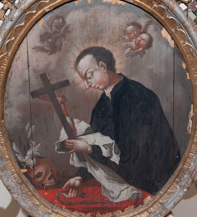 Zdjęcie nr 14: Pole obrazowe w formie stojącego owalu, ujęte profilowaną ramą dekorowaną rocaille'ową falbaną. Po bokach uszaki utworzone z wolut, rocaille'u i kratki regencyjnej, przechodzące w szczyt w formie uproszczonego baldachimu z cokołem zwieńczonym sercem, zdobionego wolutami i ornamentem roślinnym. Pod baldachimem medalion z monogramem Marii w glorii. Pole obrazowe ustawione na cokole o wolutowym kształcie nóżek i fantazyjnie wyciętej dolnej krawędzi, zamkniętym fragmentem gzymsu. W jego polu otwory na drążki. 
Na obrazie Nauczania Marii w centrum ukazana siedząca św. Anna, zwrócona w trzech czwartych w prawo, z pochyloną głową. Lewą ręką obejmuje stojącą przy jej boku Marię, prawą wskazuje na księgę leżącą na jej kolanach. Twarz ma owalną, o małych oczach skierowanych w dół, małym nosie i ustach. Nad głową ma nimb. Ubrana jest w białą suknię spodnią i zieloną suknię wierzchnią oraz jasnobrązowy płaszcz, na głowie ma biały welon. Maria ukazana w półpostaci, zwrócona jest w trzech czwartych w lewo, pochylona, w obu wyciągniętych do przodu rękach trzyma otwartą księgę na kolanach św. Anny. Twarz ma owalną, o małych oczach skierowanych w dół, małym nosie i ustach, okoloną jasnymi włosami, upiętymi z tyłu głowy, wokół niej gloria promienista. Ubrana jest w jasnoczerwoną suknię i niebieski płaszcz. W lewej części obrazu, na drugim planie stoi św. Joachim, zwrócony w trzech czwartych w lewo, z obiema dłońmi opartymi na lasce. Twarz ma owalną, o małych oczach skierowanych w dół, małym nosie i ustach, okoloną siwą brodą. Na głowie ma niebieskie nakrycie, a wokół niej nimb. Ubrany jest w jasnofioletową tunikę i niebieski płaszcz. Postacie ukazane na tle wnętrza z widocznymi arkadami. W prawej części obrazu kolumny zakryte ciemnoniebieską draperią, obszytą frędzlą, z chwostami. 
Na obrazie św. Alojzego w centrum ukazany święty w półpostaci, zwrócony profilem w prawo, pochylony nad stołem. W lewej, uniesionej ręce trzyma krucyfiks i białą tkaninę, prawa leży na stole, w dłoni trzyma dyscyplinę. Twarz ma pełną, o dużych, okrągłych oczach skierowanych w dół, dużym, garbatym nosie, pełnych ustach i wystającej brodzie. Włosy krótkie, brązowe. Ubrany jest w czarną sutannę. Stół nakryty jest czerwoną tkaniną, leży na nim czaszka, lilia i korona otwarta. Święty ukazany na tle nieba, wypełnionego obłokami, na którego tle unoszą się dwie grupy uskrzydlonych główek anielskich.

