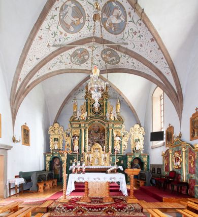 Zdjęcie nr 2: Nastawa architektoniczna, dwukondygnacyjna, pierwsza kondygnacja trójosiowa, druga jednoosiowa, z bramkami, ustawiona na cokole z wyodrębnionymi prostopadłościanami. Ołtarz murowany, w drewnianej obudowie, mensa drewniana. Boki ołtarza dekorowane malowanymi przedstawieniami nawiązującymi do alegorii Eucharystii, na prawym stół pokładny z chlebami pokładnymi, na lewym menora. Antepedium ujęte ramą, w polu trzy owalne pola, w środkowym ukazany Przybytek Świątyni Jerozolimskiej, w prawym ołtarz ofiary całopalnej, w lewym Arka Przymierza. Pola ujęte są malowanymi gałązkami oliwnymi. Oś środkowa pierwszej kondygnacji wydzielona parą kolumn o kapitelach kompozytowych, dźwigających pełne belkowanie, nad polem głównym wyłamane na kształt łuku odcinkowego, z przerwanym architrawem. Na belkowaniu fragmenty przerwanego półkolistego przyczółka z cokołami na figury św. Jadwigi Śląskiej i św. Elżbiety oraz rzeźby klęczących aniołów. Fryz dekorowany stylizowaną małżowiną i uskrzydlonymi główkami anielskimi. W polu środkowym wnęka w formie stojącego prostokąta zamkniętego łukiem odcinkowym, ujęta wąską ramą, flankowana lizenami zdobionymi wicią winnego grona. W polu obraz Wszystkich Świętych adorujących Trójcę Świętą. Na osiach bocznych nisze z konchami zdobionymi stylizowaną małżowiną, w których na wspornikach stoją figury św. Filipa i św. Jakuba Większego. Kondygnacja ujęta uszami utworzonymi z ornamentu małżowinowo-chrząstkowego i uskrzydlonych główek anielskich z czubami. 
Druga kondygnacja ustawiona na cokole, flankowana parą kolumn dźwigających pełne belkowanie, wyłamane na ich osi, oraz fragmenty zdwojonego, przerwanego, trójkątnego przyczółka z cokołami na figury św. Szczepana i św. Wawrzyńca. Fryz dekorowany małżowiną, rautami i uskrzydloną główką anielską. W centralnym punkcie belkowania cokół zakończony gzymsem, dekorowanym uskrzydloną główką anielską, z figurą św. Michała Archanioła. W polu głęboka wnęka w formie kwadratu, zamkniętego z dwóch stron łukami odcinkowymi nadwieszonymi, ujęta profilowaną ramą, z figurą Marki Boskiej Niepokalanie Poczętej, w glorii promienistej. Pole dekorowane małżowiną. 
Bramki umieszczone w przestrzeni dobudowanego do nastawy cokołu, wyodrębnione z niego. Przejścia w formie stojącego prostokąta zamkniętego łukiem półkolistym nadwieszonym, flankowane stylizowanymi pilastrami o trzonach dekorowanych stylizowaną wstęgą z akantem, dźwigającymi imposty zdobione rozetami. Na bramkach, na niskich cokołach małe aedicule z konchami, ujęte parami półkolumienek, dekorowane z trzech stron wstęgą z akantem przechodzącą w rogi obfitości z kampanulami oraz wicią roślinną z anthemionem. W aediculach figury św. Piotra i św. Pawła. Drzwiczki z malowanymi przedstawieniami św. Katarzyny Aleksandryjskiej  i św. Barbary. Struktura polichromowana w sposób imitujący marmoryzację w różnych odcieniach zieleni, kolumny, ornamentyka i profile złocone. 

