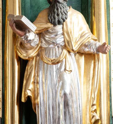 Zdjęcie nr 18: Nastawa architektoniczna, dwukondygnacyjna, pierwsza kondygnacja trójosiowa, druga jednoosiowa, z bramkami, ustawiona na cokole z wyodrębnionymi prostopadłościanami. Ołtarz murowany, w drewnianej obudowie, mensa drewniana. Boki ołtarza dekorowane malowanymi przedstawieniami nawiązującymi do alegorii Eucharystii, na prawym stół pokładny z chlebami pokładnymi, na lewym menora. Antepedium ujęte ramą, w polu trzy owalne pola, w środkowym ukazany Przybytek Świątyni Jerozolimskiej, w prawym ołtarz ofiary całopalnej, w lewym Arka Przymierza. Pola ujęte są malowanymi gałązkami oliwnymi. Oś środkowa pierwszej kondygnacji wydzielona parą kolumn o kapitelach kompozytowych, dźwigających pełne belkowanie, nad polem głównym wyłamane na kształt łuku odcinkowego, z przerwanym architrawem. Na belkowaniu fragmenty przerwanego półkolistego przyczółka z cokołami na figury św. Jadwigi Śląskiej i św. Elżbiety oraz rzeźby klęczących aniołów. Fryz dekorowany stylizowaną małżowiną i uskrzydlonymi główkami anielskimi. W polu środkowym wnęka w formie stojącego prostokąta zamkniętego łukiem odcinkowym, ujęta wąską ramą, flankowana lizenami zdobionymi wicią winnego grona. W polu obraz Wszystkich Świętych adorujących Trójcę Świętą. Na osiach bocznych nisze z konchami zdobionymi stylizowaną małżowiną, w których na wspornikach stoją figury św. Filipa i św. Jakuba Większego. Kondygnacja ujęta uszami utworzonymi z ornamentu małżowinowo-chrząstkowego i uskrzydlonych główek anielskich z czubami. 
Druga kondygnacja ustawiona na cokole, flankowana parą kolumn dźwigających pełne belkowanie, wyłamane na ich osi, oraz fragmenty zdwojonego, przerwanego, trójkątnego przyczółka z cokołami na figury św. Szczepana i św. Wawrzyńca. Fryz dekorowany małżowiną, rautami i uskrzydloną główką anielską. W centralnym punkcie belkowania cokół zakończony gzymsem, dekorowanym uskrzydloną główką anielską, z figurą św. Michała Archanioła. W polu głęboka wnęka w formie kwadratu, zamkniętego z dwóch stron łukami odcinkowymi nadwieszonymi, ujęta profilowaną ramą, z figurą Marki Boskiej Niepokalanie Poczętej, w glorii promienistej. Pole dekorowane małżowiną. 
Bramki umieszczone w przestrzeni dobudowanego do nastawy cokołu, wyodrębnione z niego. Przejścia w formie stojącego prostokąta zamkniętego łukiem półkolistym nadwieszonym, flankowane stylizowanymi pilastrami o trzonach dekorowanych stylizowaną wstęgą z akantem, dźwigającymi imposty zdobione rozetami. Na bramkach, na niskich cokołach małe aedicule z konchami, ujęte parami półkolumienek, dekorowane z trzech stron wstęgą z akantem przechodzącą w rogi obfitości z kampanulami oraz wicią roślinną z anthemionem. W aediculach figury św. Piotra i św. Pawła. Drzwiczki z malowanymi przedstawieniami św. Katarzyny Aleksandryjskiej  i św. Barbary. Struktura polichromowana w sposób imitujący marmoryzację w różnych odcieniach zieleni, kolumny, ornamentyka i profile złocone. 

