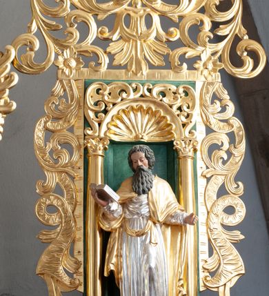 Zdjęcie nr 17: Nastawa architektoniczna, dwukondygnacyjna, pierwsza kondygnacja trójosiowa, druga jednoosiowa, z bramkami, ustawiona na cokole z wyodrębnionymi prostopadłościanami. Ołtarz murowany, w drewnianej obudowie, mensa drewniana. Boki ołtarza dekorowane malowanymi przedstawieniami nawiązującymi do alegorii Eucharystii, na prawym stół pokładny z chlebami pokładnymi, na lewym menora. Antepedium ujęte ramą, w polu trzy owalne pola, w środkowym ukazany Przybytek Świątyni Jerozolimskiej, w prawym ołtarz ofiary całopalnej, w lewym Arka Przymierza. Pola ujęte są malowanymi gałązkami oliwnymi. Oś środkowa pierwszej kondygnacji wydzielona parą kolumn o kapitelach kompozytowych, dźwigających pełne belkowanie, nad polem głównym wyłamane na kształt łuku odcinkowego, z przerwanym architrawem. Na belkowaniu fragmenty przerwanego półkolistego przyczółka z cokołami na figury św. Jadwigi Śląskiej i św. Elżbiety oraz rzeźby klęczących aniołów. Fryz dekorowany stylizowaną małżowiną i uskrzydlonymi główkami anielskimi. W polu środkowym wnęka w formie stojącego prostokąta zamkniętego łukiem odcinkowym, ujęta wąską ramą, flankowana lizenami zdobionymi wicią winnego grona. W polu obraz Wszystkich Świętych adorujących Trójcę Świętą. Na osiach bocznych nisze z konchami zdobionymi stylizowaną małżowiną, w których na wspornikach stoją figury św. Filipa i św. Jakuba Większego. Kondygnacja ujęta uszami utworzonymi z ornamentu małżowinowo-chrząstkowego i uskrzydlonych główek anielskich z czubami. 
Druga kondygnacja ustawiona na cokole, flankowana parą kolumn dźwigających pełne belkowanie, wyłamane na ich osi, oraz fragmenty zdwojonego, przerwanego, trójkątnego przyczółka z cokołami na figury św. Szczepana i św. Wawrzyńca. Fryz dekorowany małżowiną, rautami i uskrzydloną główką anielską. W centralnym punkcie belkowania cokół zakończony gzymsem, dekorowanym uskrzydloną główką anielską, z figurą św. Michała Archanioła. W polu głęboka wnęka w formie kwadratu, zamkniętego z dwóch stron łukami odcinkowymi nadwieszonymi, ujęta profilowaną ramą, z figurą Marki Boskiej Niepokalanie Poczętej, w glorii promienistej. Pole dekorowane małżowiną. 
Bramki umieszczone w przestrzeni dobudowanego do nastawy cokołu, wyodrębnione z niego. Przejścia w formie stojącego prostokąta zamkniętego łukiem półkolistym nadwieszonym, flankowane stylizowanymi pilastrami o trzonach dekorowanych stylizowaną wstęgą z akantem, dźwigającymi imposty zdobione rozetami. Na bramkach, na niskich cokołach małe aedicule z konchami, ujęte parami półkolumienek, dekorowane z trzech stron wstęgą z akantem przechodzącą w rogi obfitości z kampanulami oraz wicią roślinną z anthemionem. W aediculach figury św. Piotra i św. Pawła. Drzwiczki z malowanymi przedstawieniami św. Katarzyny Aleksandryjskiej  i św. Barbary. Struktura polichromowana w sposób imitujący marmoryzację w różnych odcieniach zieleni, kolumny, ornamentyka i profile złocone. 

