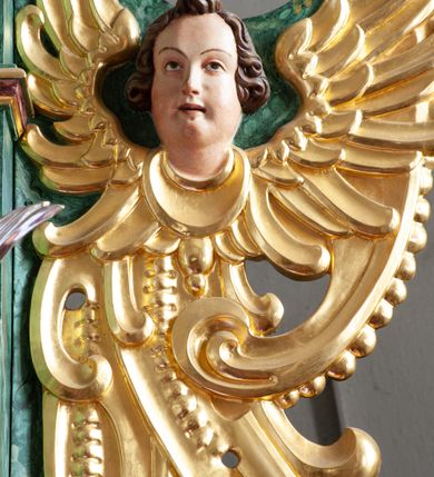 Zdjęcie nr 21: Nastawa architektoniczna, dwukondygnacyjna, pierwsza kondygnacja trójosiowa, druga jednoosiowa, z bramkami, ustawiona na cokole z wyodrębnionymi prostopadłościanami. Ołtarz murowany, w drewnianej obudowie, mensa drewniana. Boki ołtarza dekorowane malowanymi przedstawieniami nawiązującymi do alegorii Eucharystii, na prawym stół pokładny z chlebami pokładnymi, na lewym menora. Antepedium ujęte ramą, w polu trzy owalne pola, w środkowym ukazany Przybytek Świątyni Jerozolimskiej, w prawym ołtarz ofiary całopalnej, w lewym Arka Przymierza. Pola ujęte są malowanymi gałązkami oliwnymi. Oś środkowa pierwszej kondygnacji wydzielona parą kolumn o kapitelach kompozytowych, dźwigających pełne belkowanie, nad polem głównym wyłamane na kształt łuku odcinkowego, z przerwanym architrawem. Na belkowaniu fragmenty przerwanego półkolistego przyczółka z cokołami na figury św. Jadwigi Śląskiej i św. Elżbiety oraz rzeźby klęczących aniołów. Fryz dekorowany stylizowaną małżowiną i uskrzydlonymi główkami anielskimi. W polu środkowym wnęka w formie stojącego prostokąta zamkniętego łukiem odcinkowym, ujęta wąską ramą, flankowana lizenami zdobionymi wicią winnego grona. W polu obraz Wszystkich Świętych adorujących Trójcę Świętą. Na osiach bocznych nisze z konchami zdobionymi stylizowaną małżowiną, w których na wspornikach stoją figury św. Filipa i św. Jakuba Większego. Kondygnacja ujęta uszami utworzonymi z ornamentu małżowinowo-chrząstkowego i uskrzydlonych główek anielskich z czubami. 
Druga kondygnacja ustawiona na cokole, flankowana parą kolumn dźwigających pełne belkowanie, wyłamane na ich osi, oraz fragmenty zdwojonego, przerwanego, trójkątnego przyczółka z cokołami na figury św. Szczepana i św. Wawrzyńca. Fryz dekorowany małżowiną, rautami i uskrzydloną główką anielską. W centralnym punkcie belkowania cokół zakończony gzymsem, dekorowanym uskrzydloną główką anielską, z figurą św. Michała Archanioła. W polu głęboka wnęka w formie kwadratu, zamkniętego z dwóch stron łukami odcinkowymi nadwieszonymi, ujęta profilowaną ramą, z figurą Marki Boskiej Niepokalanie Poczętej, w glorii promienistej. Pole dekorowane małżowiną. 
Bramki umieszczone w przestrzeni dobudowanego do nastawy cokołu, wyodrębnione z niego. Przejścia w formie stojącego prostokąta zamkniętego łukiem półkolistym nadwieszonym, flankowane stylizowanymi pilastrami o trzonach dekorowanych stylizowaną wstęgą z akantem, dźwigającymi imposty zdobione rozetami. Na bramkach, na niskich cokołach małe aedicule z konchami, ujęte parami półkolumienek, dekorowane z trzech stron wstęgą z akantem przechodzącą w rogi obfitości z kampanulami oraz wicią roślinną z anthemionem. W aediculach figury św. Piotra i św. Pawła. Drzwiczki z malowanymi przedstawieniami św. Katarzyny Aleksandryjskiej  i św. Barbary. Struktura polichromowana w sposób imitujący marmoryzację w różnych odcieniach zieleni, kolumny, ornamentyka i profile złocone. 

