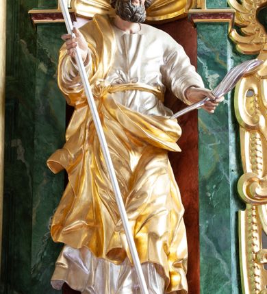 Zdjęcie nr 9: Nastawa architektoniczna, dwukondygnacyjna, pierwsza kondygnacja trójosiowa, druga jednoosiowa, z bramkami, ustawiona na cokole z wyodrębnionymi prostopadłościanami. Ołtarz murowany, w drewnianej obudowie, mensa drewniana. Boki ołtarza dekorowane malowanymi przedstawieniami nawiązującymi do alegorii Eucharystii, na prawym stół pokładny z chlebami pokładnymi, na lewym menora. Antepedium ujęte ramą, w polu trzy owalne pola, w środkowym ukazany Przybytek Świątyni Jerozolimskiej, w prawym ołtarz ofiary całopalnej, w lewym Arka Przymierza. Pola ujęte są malowanymi gałązkami oliwnymi. Oś środkowa pierwszej kondygnacji wydzielona parą kolumn o kapitelach kompozytowych, dźwigających pełne belkowanie, nad polem głównym wyłamane na kształt łuku odcinkowego, z przerwanym architrawem. Na belkowaniu fragmenty przerwanego półkolistego przyczółka z cokołami na figury św. Jadwigi Śląskiej i św. Elżbiety oraz rzeźby klęczących aniołów. Fryz dekorowany stylizowaną małżowiną i uskrzydlonymi główkami anielskimi. W polu środkowym wnęka w formie stojącego prostokąta zamkniętego łukiem odcinkowym, ujęta wąską ramą, flankowana lizenami zdobionymi wicią winnego grona. W polu obraz Wszystkich Świętych adorujących Trójcę Świętą. Na osiach bocznych nisze z konchami zdobionymi stylizowaną małżowiną, w których na wspornikach stoją figury św. Filipa i św. Jakuba Większego. Kondygnacja ujęta uszami utworzonymi z ornamentu małżowinowo-chrząstkowego i uskrzydlonych główek anielskich z czubami. 
Druga kondygnacja ustawiona na cokole, flankowana parą kolumn dźwigających pełne belkowanie, wyłamane na ich osi, oraz fragmenty zdwojonego, przerwanego, trójkątnego przyczółka z cokołami na figury św. Szczepana i św. Wawrzyńca. Fryz dekorowany małżowiną, rautami i uskrzydloną główką anielską. W centralnym punkcie belkowania cokół zakończony gzymsem, dekorowanym uskrzydloną główką anielską, z figurą św. Michała Archanioła. W polu głęboka wnęka w formie kwadratu, zamkniętego z dwóch stron łukami odcinkowymi nadwieszonymi, ujęta profilowaną ramą, z figurą Marki Boskiej Niepokalanie Poczętej, w glorii promienistej. Pole dekorowane małżowiną. 
Bramki umieszczone w przestrzeni dobudowanego do nastawy cokołu, wyodrębnione z niego. Przejścia w formie stojącego prostokąta zamkniętego łukiem półkolistym nadwieszonym, flankowane stylizowanymi pilastrami o trzonach dekorowanych stylizowaną wstęgą z akantem, dźwigającymi imposty zdobione rozetami. Na bramkach, na niskich cokołach małe aedicule z konchami, ujęte parami półkolumienek, dekorowane z trzech stron wstęgą z akantem przechodzącą w rogi obfitości z kampanulami oraz wicią roślinną z anthemionem. W aediculach figury św. Piotra i św. Pawła. Drzwiczki z malowanymi przedstawieniami św. Katarzyny Aleksandryjskiej  i św. Barbary. Struktura polichromowana w sposób imitujący marmoryzację w różnych odcieniach zieleni, kolumny, ornamentyka i profile złocone. 

