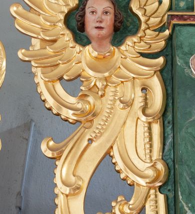 Zdjęcie nr 22: Nastawa architektoniczna, dwukondygnacyjna, pierwsza kondygnacja trójosiowa, druga jednoosiowa, z bramkami, ustawiona na cokole z wyodrębnionymi prostopadłościanami. Ołtarz murowany, w drewnianej obudowie, mensa drewniana. Boki ołtarza dekorowane malowanymi przedstawieniami nawiązującymi do alegorii Eucharystii, na prawym stół pokładny z chlebami pokładnymi, na lewym menora. Antepedium ujęte ramą, w polu trzy owalne pola, w środkowym ukazany Przybytek Świątyni Jerozolimskiej, w prawym ołtarz ofiary całopalnej, w lewym Arka Przymierza. Pola ujęte są malowanymi gałązkami oliwnymi. Oś środkowa pierwszej kondygnacji wydzielona parą kolumn o kapitelach kompozytowych, dźwigających pełne belkowanie, nad polem głównym wyłamane na kształt łuku odcinkowego, z przerwanym architrawem. Na belkowaniu fragmenty przerwanego półkolistego przyczółka z cokołami na figury św. Jadwigi Śląskiej i św. Elżbiety oraz rzeźby klęczących aniołów. Fryz dekorowany stylizowaną małżowiną i uskrzydlonymi główkami anielskimi. W polu środkowym wnęka w formie stojącego prostokąta zamkniętego łukiem odcinkowym, ujęta wąską ramą, flankowana lizenami zdobionymi wicią winnego grona. W polu obraz Wszystkich Świętych adorujących Trójcę Świętą. Na osiach bocznych nisze z konchami zdobionymi stylizowaną małżowiną, w których na wspornikach stoją figury św. Filipa i św. Jakuba Większego. Kondygnacja ujęta uszami utworzonymi z ornamentu małżowinowo-chrząstkowego i uskrzydlonych główek anielskich z czubami. 
Druga kondygnacja ustawiona na cokole, flankowana parą kolumn dźwigających pełne belkowanie, wyłamane na ich osi, oraz fragmenty zdwojonego, przerwanego, trójkątnego przyczółka z cokołami na figury św. Szczepana i św. Wawrzyńca. Fryz dekorowany małżowiną, rautami i uskrzydloną główką anielską. W centralnym punkcie belkowania cokół zakończony gzymsem, dekorowanym uskrzydloną główką anielską, z figurą św. Michała Archanioła. W polu głęboka wnęka w formie kwadratu, zamkniętego z dwóch stron łukami odcinkowymi nadwieszonymi, ujęta profilowaną ramą, z figurą Marki Boskiej Niepokalanie Poczętej, w glorii promienistej. Pole dekorowane małżowiną. 
Bramki umieszczone w przestrzeni dobudowanego do nastawy cokołu, wyodrębnione z niego. Przejścia w formie stojącego prostokąta zamkniętego łukiem półkolistym nadwieszonym, flankowane stylizowanymi pilastrami o trzonach dekorowanych stylizowaną wstęgą z akantem, dźwigającymi imposty zdobione rozetami. Na bramkach, na niskich cokołach małe aedicule z konchami, ujęte parami półkolumienek, dekorowane z trzech stron wstęgą z akantem przechodzącą w rogi obfitości z kampanulami oraz wicią roślinną z anthemionem. W aediculach figury św. Piotra i św. Pawła. Drzwiczki z malowanymi przedstawieniami św. Katarzyny Aleksandryjskiej  i św. Barbary. Struktura polichromowana w sposób imitujący marmoryzację w różnych odcieniach zieleni, kolumny, ornamentyka i profile złocone. 

