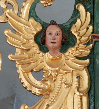 Zdjęcie nr 23: Nastawa architektoniczna, dwukondygnacyjna, pierwsza kondygnacja trójosiowa, druga jednoosiowa, z bramkami, ustawiona na cokole z wyodrębnionymi prostopadłościanami. Ołtarz murowany, w drewnianej obudowie, mensa drewniana. Boki ołtarza dekorowane malowanymi przedstawieniami nawiązującymi do alegorii Eucharystii, na prawym stół pokładny z chlebami pokładnymi, na lewym menora. Antepedium ujęte ramą, w polu trzy owalne pola, w środkowym ukazany Przybytek Świątyni Jerozolimskiej, w prawym ołtarz ofiary całopalnej, w lewym Arka Przymierza. Pola ujęte są malowanymi gałązkami oliwnymi. Oś środkowa pierwszej kondygnacji wydzielona parą kolumn o kapitelach kompozytowych, dźwigających pełne belkowanie, nad polem głównym wyłamane na kształt łuku odcinkowego, z przerwanym architrawem. Na belkowaniu fragmenty przerwanego półkolistego przyczółka z cokołami na figury św. Jadwigi Śląskiej i św. Elżbiety oraz rzeźby klęczących aniołów. Fryz dekorowany stylizowaną małżowiną i uskrzydlonymi główkami anielskimi. W polu środkowym wnęka w formie stojącego prostokąta zamkniętego łukiem odcinkowym, ujęta wąską ramą, flankowana lizenami zdobionymi wicią winnego grona. W polu obraz Wszystkich Świętych adorujących Trójcę Świętą. Na osiach bocznych nisze z konchami zdobionymi stylizowaną małżowiną, w których na wspornikach stoją figury św. Filipa i św. Jakuba Większego. Kondygnacja ujęta uszami utworzonymi z ornamentu małżowinowo-chrząstkowego i uskrzydlonych główek anielskich z czubami. 
Druga kondygnacja ustawiona na cokole, flankowana parą kolumn dźwigających pełne belkowanie, wyłamane na ich osi, oraz fragmenty zdwojonego, przerwanego, trójkątnego przyczółka z cokołami na figury św. Szczepana i św. Wawrzyńca. Fryz dekorowany małżowiną, rautami i uskrzydloną główką anielską. W centralnym punkcie belkowania cokół zakończony gzymsem, dekorowanym uskrzydloną główką anielską, z figurą św. Michała Archanioła. W polu głęboka wnęka w formie kwadratu, zamkniętego z dwóch stron łukami odcinkowymi nadwieszonymi, ujęta profilowaną ramą, z figurą Marki Boskiej Niepokalanie Poczętej, w glorii promienistej. Pole dekorowane małżowiną. 
Bramki umieszczone w przestrzeni dobudowanego do nastawy cokołu, wyodrębnione z niego. Przejścia w formie stojącego prostokąta zamkniętego łukiem półkolistym nadwieszonym, flankowane stylizowanymi pilastrami o trzonach dekorowanych stylizowaną wstęgą z akantem, dźwigającymi imposty zdobione rozetami. Na bramkach, na niskich cokołach małe aedicule z konchami, ujęte parami półkolumienek, dekorowane z trzech stron wstęgą z akantem przechodzącą w rogi obfitości z kampanulami oraz wicią roślinną z anthemionem. W aediculach figury św. Piotra i św. Pawła. Drzwiczki z malowanymi przedstawieniami św. Katarzyny Aleksandryjskiej  i św. Barbary. Struktura polichromowana w sposób imitujący marmoryzację w różnych odcieniach zieleni, kolumny, ornamentyka i profile złocone. 

