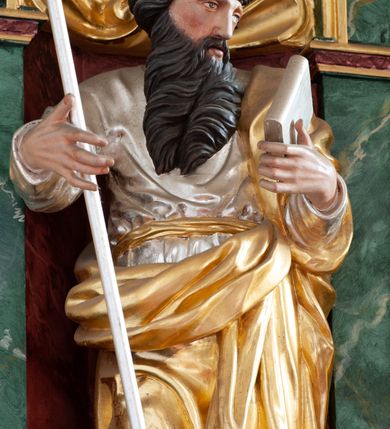 Zdjęcie nr 7: Nastawa architektoniczna, dwukondygnacyjna, pierwsza kondygnacja trójosiowa, druga jednoosiowa, z bramkami, ustawiona na cokole z wyodrębnionymi prostopadłościanami. Ołtarz murowany, w drewnianej obudowie, mensa drewniana. Boki ołtarza dekorowane malowanymi przedstawieniami nawiązującymi do alegorii Eucharystii, na prawym stół pokładny z chlebami pokładnymi, na lewym menora. Antepedium ujęte ramą, w polu trzy owalne pola, w środkowym ukazany Przybytek Świątyni Jerozolimskiej, w prawym ołtarz ofiary całopalnej, w lewym Arka Przymierza. Pola ujęte są malowanymi gałązkami oliwnymi. Oś środkowa pierwszej kondygnacji wydzielona parą kolumn o kapitelach kompozytowych, dźwigających pełne belkowanie, nad polem głównym wyłamane na kształt łuku odcinkowego, z przerwanym architrawem. Na belkowaniu fragmenty przerwanego półkolistego przyczółka z cokołami na figury św. Jadwigi Śląskiej i św. Elżbiety oraz rzeźby klęczących aniołów. Fryz dekorowany stylizowaną małżowiną i uskrzydlonymi główkami anielskimi. W polu środkowym wnęka w formie stojącego prostokąta zamkniętego łukiem odcinkowym, ujęta wąską ramą, flankowana lizenami zdobionymi wicią winnego grona. W polu obraz Wszystkich Świętych adorujących Trójcę Świętą. Na osiach bocznych nisze z konchami zdobionymi stylizowaną małżowiną, w których na wspornikach stoją figury św. Filipa i św. Jakuba Większego. Kondygnacja ujęta uszami utworzonymi z ornamentu małżowinowo-chrząstkowego i uskrzydlonych główek anielskich z czubami. 
Druga kondygnacja ustawiona na cokole, flankowana parą kolumn dźwigających pełne belkowanie, wyłamane na ich osi, oraz fragmenty zdwojonego, przerwanego, trójkątnego przyczółka z cokołami na figury św. Szczepana i św. Wawrzyńca. Fryz dekorowany małżowiną, rautami i uskrzydloną główką anielską. W centralnym punkcie belkowania cokół zakończony gzymsem, dekorowanym uskrzydloną główką anielską, z figurą św. Michała Archanioła. W polu głęboka wnęka w formie kwadratu, zamkniętego z dwóch stron łukami odcinkowymi nadwieszonymi, ujęta profilowaną ramą, z figurą Marki Boskiej Niepokalanie Poczętej, w glorii promienistej. Pole dekorowane małżowiną. 
Bramki umieszczone w przestrzeni dobudowanego do nastawy cokołu, wyodrębnione z niego. Przejścia w formie stojącego prostokąta zamkniętego łukiem półkolistym nadwieszonym, flankowane stylizowanymi pilastrami o trzonach dekorowanych stylizowaną wstęgą z akantem, dźwigającymi imposty zdobione rozetami. Na bramkach, na niskich cokołach małe aedicule z konchami, ujęte parami półkolumienek, dekorowane z trzech stron wstęgą z akantem przechodzącą w rogi obfitości z kampanulami oraz wicią roślinną z anthemionem. W aediculach figury św. Piotra i św. Pawła. Drzwiczki z malowanymi przedstawieniami św. Katarzyny Aleksandryjskiej  i św. Barbary. Struktura polichromowana w sposób imitujący marmoryzację w różnych odcieniach zieleni, kolumny, ornamentyka i profile złocone. 

