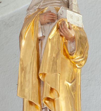 Zdjęcie nr 26: Nastawa architektoniczna, dwukondygnacyjna, pierwsza kondygnacja trójosiowa, druga jednoosiowa, z bramkami, ustawiona na cokole z wyodrębnionymi prostopadłościanami. Ołtarz murowany, w drewnianej obudowie, mensa drewniana. Boki ołtarza dekorowane malowanymi przedstawieniami nawiązującymi do alegorii Eucharystii, na prawym stół pokładny z chlebami pokładnymi, na lewym menora. Antepedium ujęte ramą, w polu trzy owalne pola, w środkowym ukazany Przybytek Świątyni Jerozolimskiej, w prawym ołtarz ofiary całopalnej, w lewym Arka Przymierza. Pola ujęte są malowanymi gałązkami oliwnymi. Oś środkowa pierwszej kondygnacji wydzielona parą kolumn o kapitelach kompozytowych, dźwigających pełne belkowanie, nad polem głównym wyłamane na kształt łuku odcinkowego, z przerwanym architrawem. Na belkowaniu fragmenty przerwanego półkolistego przyczółka z cokołami na figury św. Jadwigi Śląskiej i św. Elżbiety oraz rzeźby klęczących aniołów. Fryz dekorowany stylizowaną małżowiną i uskrzydlonymi główkami anielskimi. W polu środkowym wnęka w formie stojącego prostokąta zamkniętego łukiem odcinkowym, ujęta wąską ramą, flankowana lizenami zdobionymi wicią winnego grona. W polu obraz Wszystkich Świętych adorujących Trójcę Świętą. Na osiach bocznych nisze z konchami zdobionymi stylizowaną małżowiną, w których na wspornikach stoją figury św. Filipa i św. Jakuba Większego. Kondygnacja ujęta uszami utworzonymi z ornamentu małżowinowo-chrząstkowego i uskrzydlonych główek anielskich z czubami. 
Druga kondygnacja ustawiona na cokole, flankowana parą kolumn dźwigających pełne belkowanie, wyłamane na ich osi, oraz fragmenty zdwojonego, przerwanego, trójkątnego przyczółka z cokołami na figury św. Szczepana i św. Wawrzyńca. Fryz dekorowany małżowiną, rautami i uskrzydloną główką anielską. W centralnym punkcie belkowania cokół zakończony gzymsem, dekorowanym uskrzydloną główką anielską, z figurą św. Michała Archanioła. W polu głęboka wnęka w formie kwadratu, zamkniętego z dwóch stron łukami odcinkowymi nadwieszonymi, ujęta profilowaną ramą, z figurą Marki Boskiej Niepokalanie Poczętej, w glorii promienistej. Pole dekorowane małżowiną. 
Bramki umieszczone w przestrzeni dobudowanego do nastawy cokołu, wyodrębnione z niego. Przejścia w formie stojącego prostokąta zamkniętego łukiem półkolistym nadwieszonym, flankowane stylizowanymi pilastrami o trzonach dekorowanych stylizowaną wstęgą z akantem, dźwigającymi imposty zdobione rozetami. Na bramkach, na niskich cokołach małe aedicule z konchami, ujęte parami półkolumienek, dekorowane z trzech stron wstęgą z akantem przechodzącą w rogi obfitości z kampanulami oraz wicią roślinną z anthemionem. W aediculach figury św. Piotra i św. Pawła. Drzwiczki z malowanymi przedstawieniami św. Katarzyny Aleksandryjskiej  i św. Barbary. Struktura polichromowana w sposób imitujący marmoryzację w różnych odcieniach zieleni, kolumny, ornamentyka i profile złocone. 

