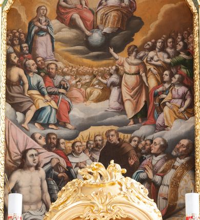 Zdjęcie nr 33: Nastawa architektoniczna, dwukondygnacyjna, pierwsza kondygnacja trójosiowa, druga jednoosiowa, z bramkami, ustawiona na cokole z wyodrębnionymi prostopadłościanami. Ołtarz murowany, w drewnianej obudowie, mensa drewniana. Boki ołtarza dekorowane malowanymi przedstawieniami nawiązującymi do alegorii Eucharystii, na prawym stół pokładny z chlebami pokładnymi, na lewym menora. Antepedium ujęte ramą, w polu trzy owalne pola, w środkowym ukazany Przybytek Świątyni Jerozolimskiej, w prawym ołtarz ofiary całopalnej, w lewym Arka Przymierza. Pola ujęte są malowanymi gałązkami oliwnymi. Oś środkowa pierwszej kondygnacji wydzielona parą kolumn o kapitelach kompozytowych, dźwigających pełne belkowanie, nad polem głównym wyłamane na kształt łuku odcinkowego, z przerwanym architrawem. Na belkowaniu fragmenty przerwanego półkolistego przyczółka z cokołami na figury św. Jadwigi Śląskiej i św. Elżbiety oraz rzeźby klęczących aniołów. Fryz dekorowany stylizowaną małżowiną i uskrzydlonymi główkami anielskimi. W polu środkowym wnęka w formie stojącego prostokąta zamkniętego łukiem odcinkowym, ujęta wąską ramą, flankowana lizenami zdobionymi wicią winnego grona. W polu obraz Wszystkich Świętych adorujących Trójcę Świętą. Na osiach bocznych nisze z konchami zdobionymi stylizowaną małżowiną, w których na wspornikach stoją figury św. Filipa i św. Jakuba Większego. Kondygnacja ujęta uszami utworzonymi z ornamentu małżowinowo-chrząstkowego i uskrzydlonych główek anielskich z czubami. 
Druga kondygnacja ustawiona na cokole, flankowana parą kolumn dźwigających pełne belkowanie, wyłamane na ich osi, oraz fragmenty zdwojonego, przerwanego, trójkątnego przyczółka z cokołami na figury św. Szczepana i św. Wawrzyńca. Fryz dekorowany małżowiną, rautami i uskrzydloną główką anielską. W centralnym punkcie belkowania cokół zakończony gzymsem, dekorowanym uskrzydloną główką anielską, z figurą św. Michała Archanioła. W polu głęboka wnęka w formie kwadratu, zamkniętego z dwóch stron łukami odcinkowymi nadwieszonymi, ujęta profilowaną ramą, z figurą Marki Boskiej Niepokalanie Poczętej, w glorii promienistej. Pole dekorowane małżowiną. 
Bramki umieszczone w przestrzeni dobudowanego do nastawy cokołu, wyodrębnione z niego. Przejścia w formie stojącego prostokąta zamkniętego łukiem półkolistym nadwieszonym, flankowane stylizowanymi pilastrami o trzonach dekorowanych stylizowaną wstęgą z akantem, dźwigającymi imposty zdobione rozetami. Na bramkach, na niskich cokołach małe aedicule z konchami, ujęte parami półkolumienek, dekorowane z trzech stron wstęgą z akantem przechodzącą w rogi obfitości z kampanulami oraz wicią roślinną z anthemionem. W aediculach figury św. Piotra i św. Pawła. Drzwiczki z malowanymi przedstawieniami św. Katarzyny Aleksandryjskiej  i św. Barbary. Struktura polichromowana w sposób imitujący marmoryzację w różnych odcieniach zieleni, kolumny, ornamentyka i profile złocone. 

