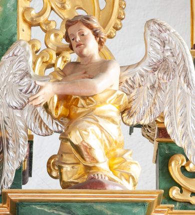 Zdjęcie nr 28: Nastawa architektoniczna, dwukondygnacyjna, pierwsza kondygnacja trójosiowa, druga jednoosiowa, z bramkami, ustawiona na cokole z wyodrębnionymi prostopadłościanami. Ołtarz murowany, w drewnianej obudowie, mensa drewniana. Boki ołtarza dekorowane malowanymi przedstawieniami nawiązującymi do alegorii Eucharystii, na prawym stół pokładny z chlebami pokładnymi, na lewym menora. Antepedium ujęte ramą, w polu trzy owalne pola, w środkowym ukazany Przybytek Świątyni Jerozolimskiej, w prawym ołtarz ofiary całopalnej, w lewym Arka Przymierza. Pola ujęte są malowanymi gałązkami oliwnymi. Oś środkowa pierwszej kondygnacji wydzielona parą kolumn o kapitelach kompozytowych, dźwigających pełne belkowanie, nad polem głównym wyłamane na kształt łuku odcinkowego, z przerwanym architrawem. Na belkowaniu fragmenty przerwanego półkolistego przyczółka z cokołami na figury św. Jadwigi Śląskiej i św. Elżbiety oraz rzeźby klęczących aniołów. Fryz dekorowany stylizowaną małżowiną i uskrzydlonymi główkami anielskimi. W polu środkowym wnęka w formie stojącego prostokąta zamkniętego łukiem odcinkowym, ujęta wąską ramą, flankowana lizenami zdobionymi wicią winnego grona. W polu obraz Wszystkich Świętych adorujących Trójcę Świętą. Na osiach bocznych nisze z konchami zdobionymi stylizowaną małżowiną, w których na wspornikach stoją figury św. Filipa i św. Jakuba Większego. Kondygnacja ujęta uszami utworzonymi z ornamentu małżowinowo-chrząstkowego i uskrzydlonych główek anielskich z czubami. 
Druga kondygnacja ustawiona na cokole, flankowana parą kolumn dźwigających pełne belkowanie, wyłamane na ich osi, oraz fragmenty zdwojonego, przerwanego, trójkątnego przyczółka z cokołami na figury św. Szczepana i św. Wawrzyńca. Fryz dekorowany małżowiną, rautami i uskrzydloną główką anielską. W centralnym punkcie belkowania cokół zakończony gzymsem, dekorowanym uskrzydloną główką anielską, z figurą św. Michała Archanioła. W polu głęboka wnęka w formie kwadratu, zamkniętego z dwóch stron łukami odcinkowymi nadwieszonymi, ujęta profilowaną ramą, z figurą Marki Boskiej Niepokalanie Poczętej, w glorii promienistej. Pole dekorowane małżowiną. 
Bramki umieszczone w przestrzeni dobudowanego do nastawy cokołu, wyodrębnione z niego. Przejścia w formie stojącego prostokąta zamkniętego łukiem półkolistym nadwieszonym, flankowane stylizowanymi pilastrami o trzonach dekorowanych stylizowaną wstęgą z akantem, dźwigającymi imposty zdobione rozetami. Na bramkach, na niskich cokołach małe aedicule z konchami, ujęte parami półkolumienek, dekorowane z trzech stron wstęgą z akantem przechodzącą w rogi obfitości z kampanulami oraz wicią roślinną z anthemionem. W aediculach figury św. Piotra i św. Pawła. Drzwiczki z malowanymi przedstawieniami św. Katarzyny Aleksandryjskiej  i św. Barbary. Struktura polichromowana w sposób imitujący marmoryzację w różnych odcieniach zieleni, kolumny, ornamentyka i profile złocone. 

