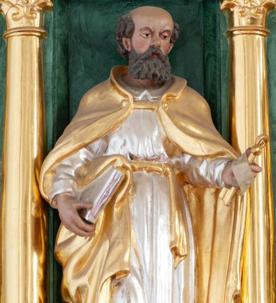 Zdjęcie nr 1: Figura ścięta z tyłu, ustawiona na niskiej podstawie. Święty ukazany frontalnie, z głową skierowaną w lewo, w kontrapoście. W lewej, uniesionej ręce trzyma klucze, w prawej, opuszczonej przy boku księgę. Twarz ma kwadratową, o okrągłych, półprzymkniętych oczach oraz uniesionych i zmarszczonych brwiach, dużym, krótkim nosie i małych ustach, okoloną falowaną brodą oraz krótkimi kręconymi włosami, z łysiną na głowie. Ubrany jest w srebrzoną tunikę z kołnierzykiem, przepasaną w talii złoconą szarfą oraz złocony płaszcz narzucony na ramiona. Polichromia ciała naturalistyczna.


