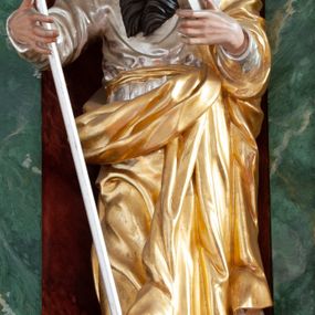 Zdjęcie nr 1: Figura ścięta z tyłu, drążona, ustawiona na niskiej podstawie imitującej skałę. Święty ukazany frontalnie, w kontrapoście, z głową skierowaną w lewo. Obie ręce ma ugięte i uniesione przed siebie, w lewej trzyma księgę, w prawej laskę. Twarz ma pociągłą, o niskim czole, wąskich, migdałowatych oczach, prostym nosie i pełnych, rozchylonych ustach, okoloną długą, silnie skręconą w dwa pukle brodą oraz krótkimi kręconymi włosami. Ubrany jest w srebrzoną tunikę przepasaną złoconą szarfą w talii oraz złocony płaszcz zarzucony na lewe ramię i zawinięty z przodu postaci. Polichromia naturalistyczna w partiach ciała. 

