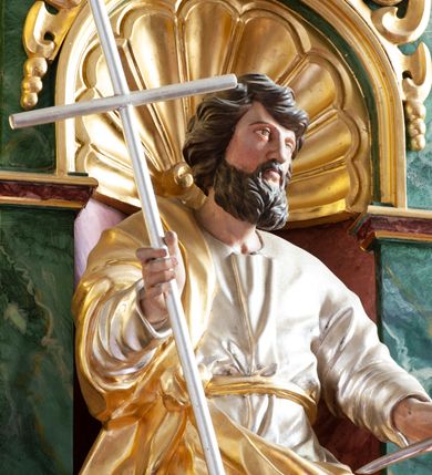 Zdjęcie nr 4: Figura ścięta z tyłu i drążona, ustawiona na niskiej podstawie w formie skały. Święty ukazany frontalnie, w kontrapoście, z głową skierowaną w lewo. Ręce ma wyciągnięte do przodu i rozłożone, w lewej dłoni ma pióro, w prawej trzyma laskę zakończoną krzyżem. Twarz ma pociągłą, o niskim czole, migdałowatych oczach, małym nosie i ustach, okoloną gęstą, silnie kręconą brodą oraz krótkimi skręconymi w pojedyncze pasma włosami. Ubrany jest w srebrzoną tunikę, przepasaną złoconą wstęgą w talii oraz złocony płaszcz zarzucony na prawe ramię i zawinięty z przodu postaci. Polichromia ciała naturalistyczna. 

