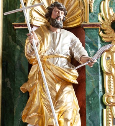 Zdjęcie nr 1: Figura ścięta z tyłu i drążona, ustawiona na niskiej podstawie w formie skały. Święty ukazany frontalnie, w kontrapoście, z głową skierowaną w lewo. Ręce ma wyciągnięte do przodu i rozłożone, w lewej dłoni ma pióro, w prawej trzyma laskę zakończoną krzyżem. Twarz ma pociągłą, o niskim czole, migdałowatych oczach, małym nosie i ustach, okoloną gęstą, silnie kręconą brodą oraz krótkimi skręconymi w pojedyncze pasma włosami. Ubrany jest w srebrzoną tunikę, przepasaną złoconą wstęgą w talii oraz złocony płaszcz zarzucony na prawe ramię i zawinięty z przodu postaci. Polichromia ciała naturalistyczna. 

