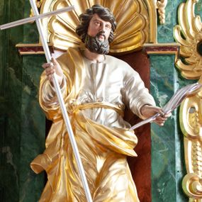 Zdjęcie nr 1: Figura ścięta z tyłu i drążona, ustawiona na niskiej podstawie w formie skały. Święty ukazany frontalnie, w kontrapoście, z głową skierowaną w lewo. Ręce ma wyciągnięte do przodu i rozłożone, w lewej dłoni ma pióro, w prawej trzyma laskę zakończoną krzyżem. Twarz ma pociągłą, o niskim czole, migdałowatych oczach, małym nosie i ustach, okoloną gęstą, silnie kręconą brodą oraz krótkimi skręconymi w pojedyncze pasma włosami. Ubrany jest w srebrzoną tunikę, przepasaną złoconą wstęgą w talii oraz złocony płaszcz zarzucony na prawe ramię i zawinięty z przodu postaci. Polichromia ciała naturalistyczna. 

