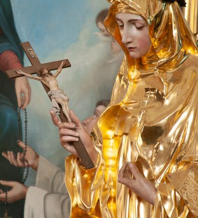 Zdjęcie nr 5: Rzeźba delikatnie ścięta z tyłu, ustawiona na niskiej podstawie. Święta ukazana frontalnie, w kontrapoście, z pochyloną głową, obie ręce ma ugięte i lekko uniesione, w prawej trzyma krucyfiks. Twarz ma owalną, o dużych oczach skierowanych w dół, prostym, wąskim nosie i ustach. Ubrana jest w złocony habit z pelerynką i szkaplerzem, złocony płaszcz o dekoracyjnej bordiurze narzucony na ramiona oraz złocony welon. Na głowie ma brązową koronę cierniową. Polichromia ciała naturalistyczna. 


