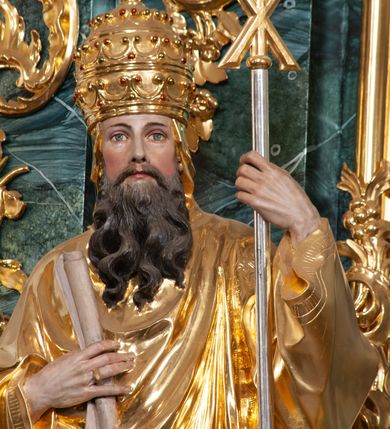 Zdjęcie nr 4: Rzeźba delikatnie ścięta z tyłu, ustawiona na niskiej podstawie. Święty zwrócony frontalnie, w kontrapoście, lewą ręką trzyma laskę zakończoną znakiem Chi Rho, w prawej, ugiętej trzyma zwój. Twarz ma pociągłą, o dużych, migdałowatych oczach, prostym nosie i małych ustach, okoloną gęstą, kręconą brodą, opadającą na pierś. Na głowie ma złoconą tiarę papieską. Ubrany jest w luźną, złoconą albę oraz złocony ornat o dekoracyjnej płaskorzeźbionej bordiurze. Polichromia ciała naturalistyczna. 