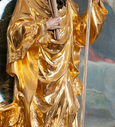 Zdjęcie nr 2: Rzeźba delikatnie ścięta z tyłu, ustawiona na niskiej podstawie. Święty zwrócony frontalnie, w kontrapoście, lewą ręką trzyma laskę zakończoną znakiem Chi Rho, w prawej, ugiętej trzyma zwój. Twarz ma pociągłą, o dużych, migdałowatych oczach, prostym nosie i małych ustach, okoloną gęstą, kręconą brodą, opadającą na pierś. Na głowie ma złoconą tiarę papieską. Ubrany jest w luźną, złoconą albę oraz złocony ornat o dekoracyjnej płaskorzeźbionej bordiurze. Polichromia ciała naturalistyczna. 