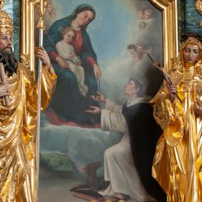 Zdjęcie nr 1: Obraz w formie stojącego prostokąta zamkniętego łukiem odcinkowym nadwieszonym z uskokiem z przedstawieniem Matki Boskiej z Dzieciątkiem przekazującej różaniec św. Dominikowi. W lewej części obrazu ukazana Maria, tronująca pośród obłoków, w pozycji siedzącej, zwrócona w trzech czwartych w lewo, pochylona. Lewą wyciągniętą przed siebie ręką podaje różaniec, prawą obejmuje Dzieciątko siedzące na jej kolanach, w dłoni trzyma berło. Maria ma owalną twarz, o okrągłych oczach skierowanych w dół, małym nosie i ustach, okoloną brązowymi włosami ukrytymi pod welonem. Wokół głowy ma nimb gwieździsty. Ubrana jest w czerwoną suknię, niebieski płaszcz zarzucony na ramiona i opadający na kolana oraz zielony welon. Dzieciątko w pozycji siedzącej, zwrócone w trzech czwartych w lewo. Prawą dłoń unosi w geście błogosławieństwa, w lewej trzyma jabłko królewskie. Twarz ma okrągłą, o dużych oczach skierowanych w dół, małym nosie i ustach, okoloną jasnymi, kręconymi, krótkimi włosami. Wokół głowy ma nimb krzyżowy. Ubrane jest w białą, długą tunikę. W prawej części obrazu, przed Marią klęczy św. Dominik, skierowany profilem w prawo, z uniesioną głową i rękami wyciągniętymi ku Marii, ujmującymi różaniec. Twarz ma szczupłą, z oczami skierowanymi w górę, dużym nosem i małymi ustami, okoloną krótkimi włosami z tonsurą na głowie. Ubrany jest w biały habit i czarny płaszcz. Na stopach ma sandały. Przed nim leży czarna księga i pies trzymający w pysku zapaloną pochodnię. W dolnej części obrazu widoczny pejzaż, w górnej niebo wypełnione chmurami i uskrzydlonymi główkami anielskimi, ułożonymi w krąg wokół Marii. 