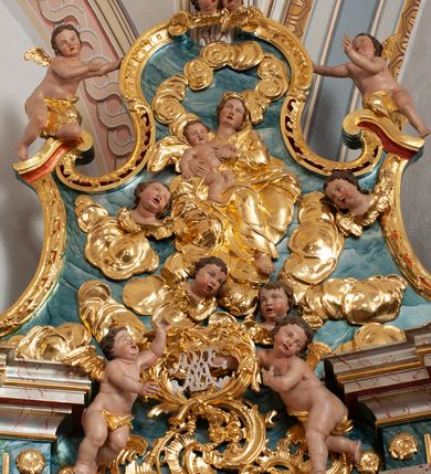 Zdjęcie nr 12: Nastawa architektoniczna, jednoosiowa, jednokondygnacyjna ze zwieńczeniem, ustawiona na dwustrefowym cokole z wyodrębnionymi prostopadłościanami, ustawionymi pod kątem. Ołtarz sarkofagowy, wklęsło-wypukły, dekorowany w narożach ornamentem roślinnym, w polu zaś rocaille&#039;owym kartuszem. Mensa szersza, drewniana. Nastawa na planie półowalu, ujęta dwiema parami pilastrów i stojącą na ich tle parą kolumn o kapitelach kompozytowych. Podpory dźwigają pełne belkowanie, wyłamane półkoliście na ich osi, przerwane nad polem środkowym. Fryz dekorowany rozetami, cokoły rocaille&#039;m, a trzony pilastrów rocaille&#039;m i zwisami roślinnymi. W polu środkowym wnęka w formie stojącego prostokąta zamkniętego łukiem odcinkowym nadwieszonym z uskokiem, ujęta profilowaną ramą, zwieńczoną rocaille&#039;owym szczytem, z aniołkami podtrzymującymi kartusz z monogramem Marii, w polu obraz Matki Boskiej Różańcowej ze św. Dominikiem. Wnękę flankują figury św. Piusa V i św. Katarzyny Sieneńskiej ustawione na rocaille&#039;owych wspornikach. Na zewnętrzych krawędziach cokołu siedzą figury aniołów. Zwieńczenie o fantazyjnej, wklęsło-wypukłej formie, z uszakami i puttami, ujęte wolutami spływającymi na belkowanie, na których siedzą putta; obwiedzione rocaille&#039;m, zakończone dwiema uskrzydlonymi główkami anielskimi. W polu płaskorzeźbione przedstawienie Matki Boskiej z Dzieciątkiem tronującej pośród obłoków i uskrzydlonych główek anielskich. Struktura polichromowana na sposób imitujący marmoryzację w różnych odcieniach zieleni, kolumny, ornamentyka i profile złocone, niektóre profile srebrzone. 