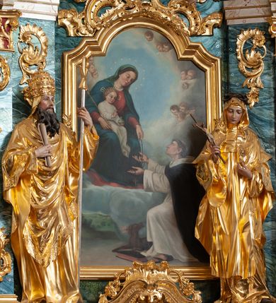 Zdjęcie nr 30: Nastawa architektoniczna, jednoosiowa, jednokondygnacyjna ze zwieńczeniem, ustawiona na dwustrefowym cokole z wyodrębnionymi prostopadłościanami, ustawionymi pod kątem. Ołtarz sarkofagowy, wklęsło-wypukły, dekorowany w narożach ornamentem roślinnym, w polu zaś rocaille&#039;owym kartuszem. Mensa szersza, drewniana. Nastawa na planie półowalu, ujęta dwiema parami pilastrów i stojącą na ich tle parą kolumn o kapitelach kompozytowych. Podpory dźwigają pełne belkowanie, wyłamane półkoliście na ich osi, przerwane nad polem środkowym. Fryz dekorowany rozetami, cokoły rocaille&#039;m, a trzony pilastrów rocaille&#039;m i zwisami roślinnymi. W polu środkowym wnęka w formie stojącego prostokąta zamkniętego łukiem odcinkowym nadwieszonym z uskokiem, ujęta profilowaną ramą, zwieńczoną rocaille&#039;owym szczytem, z aniołkami podtrzymującymi kartusz z monogramem Marii, w polu obraz Matki Boskiej Różańcowej ze św. Dominikiem. Wnękę flankują figury św. Piusa V i św. Katarzyny Sieneńskiej ustawione na rocaille&#039;owych wspornikach. Na zewnętrzych krawędziach cokołu siedzą figury aniołów. Zwieńczenie o fantazyjnej, wklęsło-wypukłej formie, z uszakami i puttami, ujęte wolutami spływającymi na belkowanie, na których siedzą putta; obwiedzione rocaille&#039;m, zakończone dwiema uskrzydlonymi główkami anielskimi. W polu płaskorzeźbione przedstawienie Matki Boskiej z Dzieciątkiem tronującej pośród obłoków i uskrzydlonych główek anielskich. Struktura polichromowana na sposób imitujący marmoryzację w różnych odcieniach zieleni, kolumny, ornamentyka i profile złocone, niektóre profile srebrzone. 