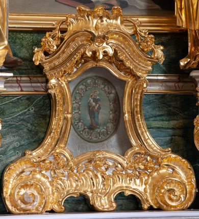 Zdjęcie nr 26: Nastawa architektoniczna, jednoosiowa, jednokondygnacyjna ze zwieńczeniem, ustawiona na dwustrefowym cokole z wyodrębnionymi prostopadłościanami, ustawionymi pod kątem. Ołtarz sarkofagowy, wklęsło-wypukły, dekorowany w narożach ornamentem roślinnym, w polu zaś rocaille'owym kartuszem. Mensa szersza, drewniana. Nastawa na planie półowalu, ujęta dwiema parami pilastrów i stojącą na ich tle parą kolumn o kapitelach kompozytowych. Podpory dźwigają pełne belkowanie, wyłamane półkoliście na ich osi, przerwane nad polem środkowym. Fryz dekorowany rozetami, cokoły rocaille'm, a trzony pilastrów rocaille'm i zwisami roślinnymi. W polu środkowym wnęka w formie stojącego prostokąta zamkniętego łukiem odcinkowym nadwieszonym z uskokiem, ujęta profilowaną ramą, zwieńczoną rocaille'owym szczytem, z aniołkami podtrzymującymi kartusz z monogramem Marii, w polu obraz Matki Boskiej Różańcowej ze św. Dominikiem. Wnękę flankują figury św. Piusa V i św. Katarzyny Sieneńskiej ustawione na rocaille'owych wspornikach. Na zewnętrzych krawędziach cokołu siedzą figury aniołów. Zwieńczenie o fantazyjnej, wklęsło-wypukłej formie, z uszakami i puttami, ujęte wolutami spływającymi na belkowanie, na których siedzą putta; obwiedzione rocaille'm, zakończone dwiema uskrzydlonymi główkami anielskimi. W polu płaskorzeźbione przedstawienie Matki Boskiej z Dzieciątkiem tronującej pośród obłoków i uskrzydlonych główek anielskich. Struktura polichromowana na sposób imitujący marmoryzację w różnych odcieniach zieleni, kolumny, ornamentyka i profile złocone, niektóre profile srebrzone. 