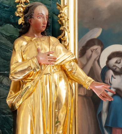 Zdjęcie nr 1: Rzeźba ścięta z tyłu, drążona, ustawiona na niskiej podstawie. Święty ukazany frontalnie, w kontrapoście, z głową skierowaną w lewo, o sylwetce delikatnie przechylonej w tył. Prawą rękę kładzie na piersi, lewą wyciąga przed siebie. Twarz ma pełną, o  wysokim czole, wąskich, migdałowatych oczach, długim, prostym nosie i pełnych, rozchylonych ustach. Włosy ma kręcone, przylegające do głowy, sięgające ramion. Ubrany jest w długą, przylegającą do ciała tunikę z kołnierzykiem, przepasaną w talii, z długimi rękawami z wywiniętymi mankietami oraz złocony płaszcz przewiązany diagonalnie przez lewe ramię, zawieszony na taśmie. Polichromia ciała naturalistyczna. 

