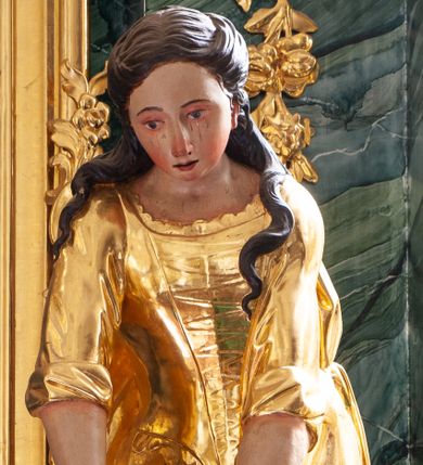 Zdjęcie nr 1: Rzeźba ścięta z tyłu, drążona, ustawiona na niskiej podstawie. Święta ukazana frontalnie, w wykroku, silnie pochylona do przodu, ze splecionymi dłońmi wyciągniętymi przed siebie.  Twarz ma pełną, o wysokim czole, wąskich, migdałowatych oczach z malowanymi łzami, prostym, długim nosie i pełnych, rozchylonych ustach. Włosy ma długie, falowane, częściowo upięte z tyłu głowy i opadające na plecy. Ubrana jest w złoconą, długą suknię, z podwiniętymi rękawami, wiązany z przodu gorset, z dekoracyjnym obszyciem oraz złocony płaszcz zarzucony na plecy i podtrzymywany na taśmie zawiniętej wokół bioder. Polichromia ciała naturalistyczna. 


