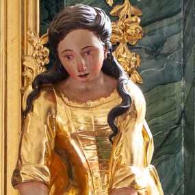 Zdjęcie nr 1: Rzeźba ścięta z tyłu, drążona, ustawiona na niskiej podstawie. Święta ukazana frontalnie, w wykroku, silnie pochylona do przodu, ze splecionymi dłońmi wyciągniętymi przed siebie.  Twarz ma pełną, o wysokim czole, wąskich, migdałowatych oczach z malowanymi łzami, prostym, długim nosie i pełnych, rozchylonych ustach. Włosy ma długie, falowane, częściowo upięte z tyłu głowy i opadające na plecy. Ubrana jest w złoconą, długą suknię, z podwiniętymi rękawami, wiązany z przodu gorset, z dekoracyjnym obszyciem oraz złocony płaszcz zarzucony na plecy i podtrzymywany na taśmie zawiniętej wokół bioder. Polichromia ciała naturalistyczna. 


