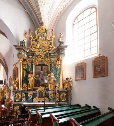Zdjęcie nr 2: Nastawa architektoniczna, jednoosiowa, jednokondygnacyjna ze zwieńczeniem, ustawiona na dwustrefowym cokole z wyodrębnionymi prostopadłościanami, ustawionymi pod kątem. Ołtarz sarkofagowy, wklęsło-wypukły, dekorowany w narożach ornamentem roślinnym, w polu zaś rocaille'owym kartuszem. Mensa szersza, drewniana. Nastawa na planie półowalu, ujęta dwiema parami pilastrów i stojącą na ich tle parą kolumn o kapitelach kompozytowych. Podpory dźwigają pełne belkowanie, wyłamane półkoliście na ich osi, przerwane nad polem środkowym. Fryz dekorowany rozetami, cokoły rocaille'm, a trzony pilastrów rocaille'm i zwisami roślinnymi. W polu środkowym wnęka w formie stojącego prostokąta zamkniętego łukiem odcinkowym nadwieszonym z uskokiem, ujęta profilowaną ramą, zwieńczoną rocaille'owym szczytem, w polu obraz zdjęcia z krzyża. Wnękę flankują figury św. Jana Ewangelisty i św. Marii Magdaleny ustawione na rocaille'owych wspornikach. Na zewnętrzych krawędziach cokołu siedzą figury aniołów z arma Christi. Zwieńczenie o fantazyjnej, wklęsło-wypukłej formie, z uszakami i puttami, ujęte wolutami spływającymi na belkowanie, na których siedzą putta; obwiedzione rocaille'm, zakończone dwiema uskrzydlonymi główkami anielskimi. W polu płaskorzeźbione przedstawienie Boga Ojca tronującego pośród obłoków i uskrzydlonych główek anielskich. Struktura polichromowana na sposób imitujący marmoryzacje w różnych odcieniach zieleni, kolumny, ornamentyka i profile złocone, niektóre profile srebrzone. 