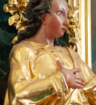 Zdjęcie nr 6: Nastawa architektoniczna, jednoosiowa, jednokondygnacyjna ze zwieńczeniem, ustawiona na dwustrefowym cokole z wyodrębnionymi prostopadłościanami, ustawionymi pod kątem. Ołtarz sarkofagowy, wklęsło-wypukły, dekorowany w narożach ornamentem roślinnym, w polu zaś rocaille'owym kartuszem. Mensa szersza, drewniana. Nastawa na planie półowalu, ujęta dwiema parami pilastrów i stojącą na ich tle parą kolumn o kapitelach kompozytowych. Podpory dźwigają pełne belkowanie, wyłamane półkoliście na ich osi, przerwane nad polem środkowym. Fryz dekorowany rozetami, cokoły rocaille'm, a trzony pilastrów rocaille'm i zwisami roślinnymi. W polu środkowym wnęka w formie stojącego prostokąta zamkniętego łukiem odcinkowym nadwieszonym z uskokiem, ujęta profilowaną ramą, zwieńczoną rocaille'owym szczytem, w polu obraz zdjęcia z krzyża. Wnękę flankują figury św. Jana Ewangelisty i św. Marii Magdaleny ustawione na rocaille'owych wspornikach. Na zewnętrzych krawędziach cokołu siedzą figury aniołów z arma Christi. Zwieńczenie o fantazyjnej, wklęsło-wypukłej formie, z uszakami i puttami, ujęte wolutami spływającymi na belkowanie, na których siedzą putta; obwiedzione rocaille'm, zakończone dwiema uskrzydlonymi główkami anielskimi. W polu płaskorzeźbione przedstawienie Boga Ojca tronującego pośród obłoków i uskrzydlonych główek anielskich. Struktura polichromowana na sposób imitujący marmoryzacje w różnych odcieniach zieleni, kolumny, ornamentyka i profile złocone, niektóre profile srebrzone. 