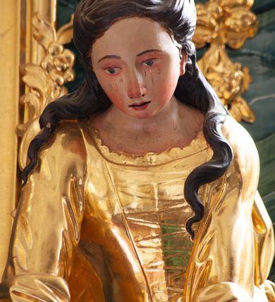 Zdjęcie nr 14: Nastawa architektoniczna, jednoosiowa, jednokondygnacyjna ze zwieńczeniem, ustawiona na dwustrefowym cokole z wyodrębnionymi prostopadłościanami, ustawionymi pod kątem. Ołtarz sarkofagowy, wklęsło-wypukły, dekorowany w narożach ornamentem roślinnym, w polu zaś rocaille&#039;owym kartuszem. Mensa szersza, drewniana. Nastawa na planie półowalu, ujęta dwiema parami pilastrów i stojącą na ich tle parą kolumn o kapitelach kompozytowych. Podpory dźwigają pełne belkowanie, wyłamane półkoliście na ich osi, przerwane nad polem środkowym. Fryz dekorowany rozetami, cokoły rocaille&#039;m, a trzony pilastrów rocaille&#039;m i zwisami roślinnymi. W polu środkowym wnęka w formie stojącego prostokąta zamkniętego łukiem odcinkowym nadwieszonym z uskokiem, ujęta profilowaną ramą, zwieńczoną rocaille&#039;owym szczytem, w polu obraz zdjęcia z krzyża. Wnękę flankują figury św. Jana Ewangelisty i św. Marii Magdaleny ustawione na rocaille&#039;owych wspornikach. Na zewnętrzych krawędziach cokołu siedzą figury aniołów z arma Christi. Zwieńczenie o fantazyjnej, wklęsło-wypukłej formie, z uszakami i puttami, ujęte wolutami spływającymi na belkowanie, na których siedzą putta; obwiedzione rocaille&#039;m, zakończone dwiema uskrzydlonymi główkami anielskimi. W polu płaskorzeźbione przedstawienie Boga Ojca tronującego pośród obłoków i uskrzydlonych główek anielskich. Struktura polichromowana na sposób imitujący marmoryzacje w różnych odcieniach zieleni, kolumny, ornamentyka i profile złocone, niektóre profile srebrzone. 