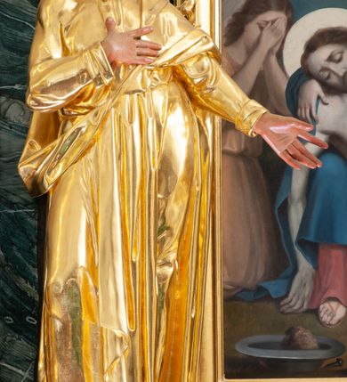 Zdjęcie nr 3: Nastawa architektoniczna, jednoosiowa, jednokondygnacyjna ze zwieńczeniem, ustawiona na dwustrefowym cokole z wyodrębnionymi prostopadłościanami, ustawionymi pod kątem. Ołtarz sarkofagowy, wklęsło-wypukły, dekorowany w narożach ornamentem roślinnym, w polu zaś rocaille&#039;owym kartuszem. Mensa szersza, drewniana. Nastawa na planie półowalu, ujęta dwiema parami pilastrów i stojącą na ich tle parą kolumn o kapitelach kompozytowych. Podpory dźwigają pełne belkowanie, wyłamane półkoliście na ich osi, przerwane nad polem środkowym. Fryz dekorowany rozetami, cokoły rocaille&#039;m, a trzony pilastrów rocaille&#039;m i zwisami roślinnymi. W polu środkowym wnęka w formie stojącego prostokąta zamkniętego łukiem odcinkowym nadwieszonym z uskokiem, ujęta profilowaną ramą, zwieńczoną rocaille&#039;owym szczytem, w polu obraz zdjęcia z krzyża. Wnękę flankują figury św. Jana Ewangelisty i św. Marii Magdaleny ustawione na rocaille&#039;owych wspornikach. Na zewnętrzych krawędziach cokołu siedzą figury aniołów z arma Christi. Zwieńczenie o fantazyjnej, wklęsło-wypukłej formie, z uszakami i puttami, ujęte wolutami spływającymi na belkowanie, na których siedzą putta; obwiedzione rocaille&#039;m, zakończone dwiema uskrzydlonymi główkami anielskimi. W polu płaskorzeźbione przedstawienie Boga Ojca tronującego pośród obłoków i uskrzydlonych główek anielskich. Struktura polichromowana na sposób imitujący marmoryzacje w różnych odcieniach zieleni, kolumny, ornamentyka i profile złocone, niektóre profile srebrzone. 