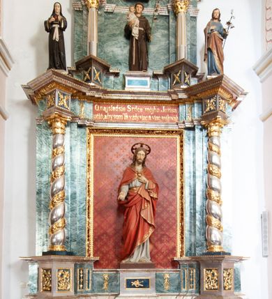 Zdjęcie nr 1: Nastawa architektoniczna, jednoosiowa, dwukondygnacyjna ze zwieńczeniem, ustawiona na dwustrefowym cokole z wyłamanymi pod kątem prostopadłościanami. Ołtarz sarkofagowy, wklęsło-wypukły, na wysokim cokole, dekorowany w narożach ornamentem roślinnym i rocaille'owym kartuszem w polu. Mensa szersza od ołtarza, drewniana. Nastawa ujęta parą kolumn o skręconych trzonach zdobionych wicią roślinną, podtrzymujących pełne belkowanie, wyłamane na ich osi pod kątem. Fryz i cokół na linii kolumn dekorowany płycinami z ornamentem roślinnym, na belkowaniu ustawione figury św. Teresy i św. Józefa. W środkowej części fryzu napis „O najsladsie Srdce môjho Ježiša / učíň, aby som Ta vždy viac a viac milovah”. Całe pole główne wypełnia wnęka ujęta ramą dekorowaną ornamentem roślinnym, z tłem złożonym z kratki i krzyży. Na jej tle, na cokole ustawiona figura Najświętszego Serca Jezusa. Druga kondygnacja węższa, ustawiona na cokole z wyłamanymi pod kątem prostopadłościanami; ujęta parą kolumn podtrzymującą pełne belkowanie, wyłamane na ich osi pod kątem, na nim dwie figurki aniołów. W polu figura św. Antoniego Padewskiego ustawiona na cokole. Zwieńczenie w formie leżącego prostokąta zamkniętego gzymsem przyjmującym kształt łuku półkolistego, dekorowanego ornamentem roślinnym, zwieńczonego krzyżem. W polu medalion z monogramem IHS w glorii promienistej, na wypukłym, półokrągłym cokole. Struktura polichromowana na sposób imitujący marmoryzację w kolorze zielono-białym, z czerwonymi detalami, kolumny, profile oraz ornamentyka złocone i srebrzone.  
