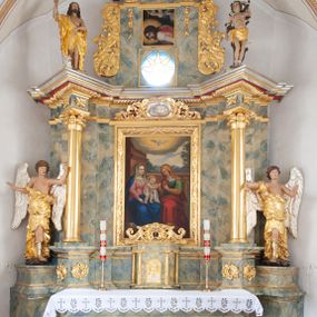 Zdjęcie nr 1: Nastawa architektoniczna, jednoosiowa, jednokondygnacyjna ze zwieńczeniem, ustawiona na dwustrefowym, szerszym cokole, z wyodrębnionymi dwiema parami prostopadłościanów, zwróconymi pod kątem. Ołtarz drewniany, sarkofagowy, wklęsło-wypukły, ustawiony na cokole. Mensa drewniana. Na ołtarzu tabernakulum w formie drewnianej skrzynki, ustawionej na cokole, flankowanej dwiema parami kolumienek, podtrzymujących belkowanie. Drzwiczki w kształcie stojącego prostokąta zamkniętego łukiem półkolistym z przedstawieniem kielicha z hostią w glorii. Całość zwieńczona szczytem utworzonym z rocaille'u i akantu. Nastawa ujęta parą kolumn podtrzymujących pełne belkowanie, z silnie wysuniętym gzymsem, wyłamane pod kątem na ich osi. W partii fryzu kartusz ujęty ornamentem roślinnym z monogramem św. Anny. Na belkowaniu ustawione figury św. Jana Chrzciciela i św. Sebastiana. W polu środkowym wnęka w formie stojącego prostokąta w wąskiej ramie, w niej obraz św. Anny Samotrzeć, w osobnej ramie dekorowanej płaskorzeźbionym wieńcem laurowym. Kondygnację flankują dwie figury aniołów ustawione na krawędzi cokołu nastawy. Zwieńczenie w formie stojącego prostokąta flankowane pilastrami podtrzymującymi pełne belkowanie wyłamane na ich osi. Trzony dekorowane zwisami. Całość zakończona szczytem w postaci stylizowanego anthemionu z karbowaną wstęgą. W polu obraz ubiczowanego Chrystusa w formie kwadratu, w ramie oraz pod nim prześwit z okrągłym oknem witrażowym w ramie o kształcie kwadratu. Zwieńczenie ujęte uszami utworzonymi z akantu i karbowanej wstęgi. Struktura polichromowana na sposób imitujący marmoryzację w kolorze żółto-zielonym, z czerwonymi detalami, kolumny, ornamentyka i profile złocone, część profili srebrzona. 