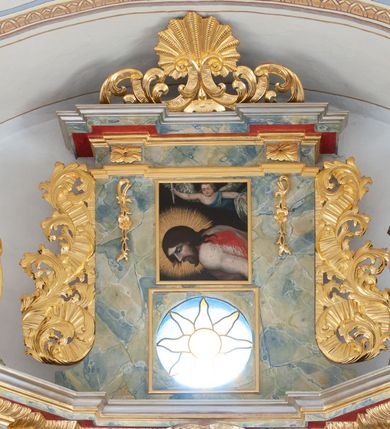 Zdjęcie nr 11: Nastawa architektoniczna, jednoosiowa, jednokondygnacyjna ze zwieńczeniem, ustawiona na dwustrefowym, szerszym cokole, z wyodrębnionymi dwiema parami prostopadłościanów, zwróconymi pod kątem. Ołtarz drewniany, sarkofagowy, wklęsło-wypukły, ustawiony na cokole. Mensa drewniana. Na ołtarzu tabernakulum w formie drewnianej skrzynki, ustawionej na cokole, flankowanej dwiema parami kolumienek, podtrzymujących belkowanie. Drzwiczki w kształcie stojącego prostokąta zamkniętego łukiem półkolistym z przedstawieniem kielicha z hostią w glorii. Całość zwieńczona szczytem utworzonym z rocaille'u i akantu. Nastawa ujęta parą kolumn podtrzymujących pełne belkowanie, z silnie wysuniętym gzymsem, wyłamane pod kątem na ich osi. W partii fryzu kartusz ujęty ornamentem roślinnym z monogramem św. Anny. Na belkowaniu ustawione figury św. Jana Chrzciciela i św. Sebastiana. W polu środkowym wnęka w formie stojącego prostokąta w wąskiej ramie, w niej obraz św. Anny Samotrzeć, w osobnej ramie dekorowanej płaskorzeźbionym wieńcem laurowym. Kondygnację flankują dwie figury aniołów ustawione na krawędzi cokołu nastawy. Zwieńczenie w formie stojącego prostokąta flankowane pilastrami podtrzymującymi pełne belkowanie wyłamane na ich osi. Trzony dekorowane zwisami. Całość zakończona szczytem w postaci stylizowanego anthemionu z karbowaną wstęgą. W polu obraz ubiczowanego Chrystusa w formie kwadratu, w ramie oraz pod nim prześwit z okrągłym oknem witrażowym w ramie o kształcie kwadratu. Zwieńczenie ujęte uszami utworzonymi z akantu i karbowanej wstęgi. Struktura polichromowana na sposób imitujący marmoryzację w kolorze żółto-zielonym, z czerwonymi detalami, kolumny, ornamentyka i profile złocone, część profili srebrzona. 
