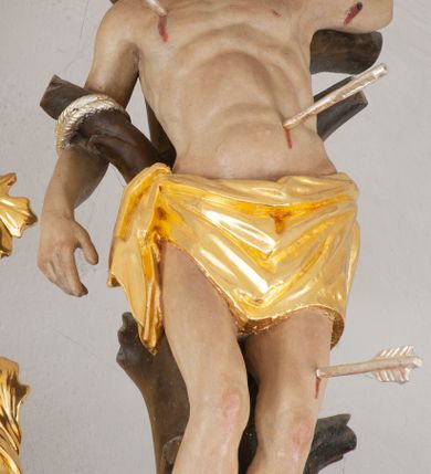 Zdjęcie nr 15: Nastawa architektoniczna, jednoosiowa, jednokondygnacyjna ze zwieńczeniem, ustawiona na dwustrefowym, szerszym cokole, z wyodrębnionymi dwiema parami prostopadłościanów, zwróconymi pod kątem. Ołtarz drewniany, sarkofagowy, wklęsło-wypukły, ustawiony na cokole. Mensa drewniana. Na ołtarzu tabernakulum w formie drewnianej skrzynki, ustawionej na cokole, flankowanej dwiema parami kolumienek, podtrzymujących belkowanie. Drzwiczki w kształcie stojącego prostokąta zamkniętego łukiem półkolistym z przedstawieniem kielicha z hostią w glorii. Całość zwieńczona szczytem utworzonym z rocaille&#039;u i akantu. Nastawa ujęta parą kolumn podtrzymujących pełne belkowanie, z silnie wysuniętym gzymsem, wyłamane pod kątem na ich osi. W partii fryzu kartusz ujęty ornamentem roślinnym z monogramem św. Anny. Na belkowaniu ustawione figury św. Jana Chrzciciela i św. Sebastiana. W polu środkowym wnęka w formie stojącego prostokąta w wąskiej ramie, w niej obraz św. Anny Samotrzeć, w osobnej ramie dekorowanej płaskorzeźbionym wieńcem laurowym. Kondygnację flankują dwie figury aniołów ustawione na krawędzi cokołu nastawy. Zwieńczenie w formie stojącego prostokąta flankowane pilastrami podtrzymującymi pełne belkowanie wyłamane na ich osi. Trzony dekorowane zwisami. Całość zakończona szczytem w postaci stylizowanego anthemionu z karbowaną wstęgą. W polu obraz ubiczowanego Chrystusa w formie kwadratu, w ramie oraz pod nim prześwit z okrągłym oknem witrażowym w ramie o kształcie kwadratu. Zwieńczenie ujęte uszami utworzonymi z akantu i karbowanej wstęgi. Struktura polichromowana na sposób imitujący marmoryzację w kolorze żółto-zielonym, z czerwonymi detalami, kolumny, ornamentyka i profile złocone, część profili srebrzona. 