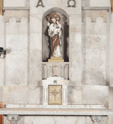 Zdjęcie nr 2: Ołtarz przyścienny, trójosiowy, jednokondygnacyjny, o formach architektonicznych, ustawiony na jednostopniowym podwyższeniu. Mensa kamienna, wsparta na dwóch półkolumnach o gładkich trzonach i kostkowych kapitelach z motywem krzyża greckiego. Antepedium gładkie, w formie alabastrowej płyty z umieszczonym centralnie metalowym krzyżem. Retabulum umieszczone na wysokim cokole. Oś środkowa nieco wyższa od osi skrajnych i wysunięta do przodu mieści zamkniętą półkoliście niszę z ustawioną na postumencie figurą przedstawiającą św. Józefa z Dzieciątkiem Jezus. Powyżej niszy litery „Α” (álfa) i „Ω” (oméga). W zwieńczeniu płaskorzeźbione przedstawienie kielicha z hostią ujętego wieńcem, w okrągłym polu zakończonym krzyżem. Osie skrajne nastawy nieco niższe, zwieńczone fryzem arkadowym. W osi ołtarza alabastrowe tabernakulum ujęte parą półkolumn o gładkich trzonach i kostkowych kapitelach. Drzwiczki metalowe z motywem krzyża.

