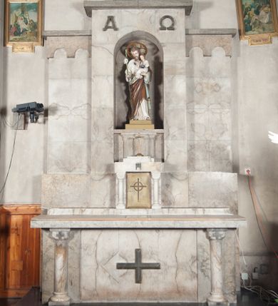 Zdjęcie nr 1: Ołtarz przyścienny, trójosiowy, jednokondygnacyjny, o formach architektonicznych, ustawiony na jednostopniowym podwyższeniu. Mensa kamienna, wsparta na dwóch półkolumnach o gładkich trzonach i kostkowych kapitelach z motywem krzyża greckiego. Antepedium gładkie, w formie alabastrowej płyty z umieszczonym centralnie metalowym krzyżem. Retabulum umieszczone na wysokim cokole. Oś środkowa nieco wyższa od osi skrajnych i wysunięta do przodu mieści zamkniętą półkoliście niszę z ustawioną na postumencie figurą przedstawiającą św. Józefa z Dzieciątkiem Jezus. Powyżej niszy litery „Α” (álfa) i „Ω” (oméga). W zwieńczeniu płaskorzeźbione przedstawienie kielicha z hostią ujętego wieńcem, w okrągłym polu zakończonym krzyżem. Osie skrajne nastawy nieco niższe, zwieńczone fryzem arkadowym. W osi ołtarza alabastrowe tabernakulum ujęte parą półkolumn o gładkich trzonach i kostkowych kapitelach. Drzwiczki metalowe z motywem krzyża.

