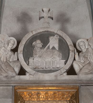 Zdjęcie nr 5: Ołtarz przyścienny, architektoniczny, pięcioosiowy, dwukondygnacyjny ze zwieńczeniem. Mensa kamienna, w formie stołu wsparta na parach kolumn o kostkowych kapitelach. Antepedium również kamienne, z umieszczonym w centrum monogramem IHS zwieńczonym krzyżem. Kondygnacja pierwsza artykułowana pięcioma arkadami ujętymi kolumienkami o kostkowych kapitelach. W arkadach umieszczone płaskorzeźbione postaci czterech ewangelistów: Jana, Marka, Łukasza i Mateusza. W osi środkowej prostopadłościenne, alabastrowe tabernakulum z tronem wystawienia nakrytym kamiennym baldachimem w formie kopuły wspartej na czterech kolumnach o kostkowych kapitelach. Na drzwiczkach umieszczony krzyż na tle glorii promienistej flankowany przez postaci klęczących aniołów. Kondygnacja druga artykułowana arkadami wspartymi na kolumnach o kostkowych kapitelach. W arkadach umieszczone dary wotywne. W osi środkowej znajduje się obraz Matki Boskiej z Dzieciątkiem w prostokątnej, złotej ramie. Struktura zwieńczona profilowanym gzymsem, ponad którym umieszczono płaskorzeźbione przedstawienie Baranka Apokaliptycznego ujętego medalionem zwieńczonym krzyżem oraz flankowanego przez postaci dwóch klęczących aniołów.
