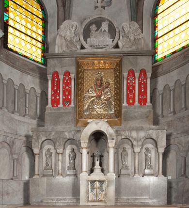Zdjęcie nr 1: Ołtarz przyścienny, architektoniczny, pięcioosiowy, dwukondygnacyjny ze zwieńczeniem. Mensa kamienna, w formie stołu wsparta na parach kolumn o kostkowych kapitelach. Antepedium również kamienne, z umieszczonym w centrum monogramem IHS zwieńczonym krzyżem. Kondygnacja pierwsza artykułowana pięcioma arkadami ujętymi kolumienkami o kostkowych kapitelach. W arkadach umieszczone płaskorzeźbione postaci czterech ewangelistów: Jana, Marka, Łukasza i Mateusza. W osi środkowej prostopadłościenne, alabastrowe tabernakulum z tronem wystawienia nakrytym kamiennym baldachimem w formie kopuły wspartej na czterech kolumnach o kostkowych kapitelach. Na drzwiczkach umieszczony krzyż na tle glorii promienistej flankowany przez postaci klęczących aniołów. Kondygnacja druga artykułowana arkadami wspartymi na kolumnach o kostkowych kapitelach. W arkadach umieszczone dary wotywne. W osi środkowej znajduje się obraz Matki Boskiej z Dzieciątkiem w prostokątnej, złotej ramie. Struktura zwieńczona profilowanym gzymsem, ponad którym umieszczono płaskorzeźbione przedstawienie Baranka Apokaliptycznego ujętego medalionem zwieńczonym krzyżem oraz flankowanego przez postaci dwóch klęczących aniołów.

