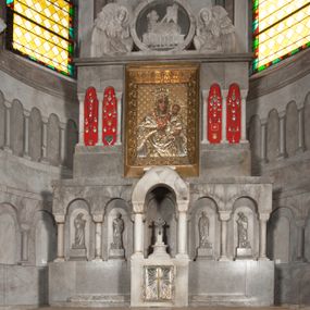 Zdjęcie nr 1: Ołtarz przyścienny, architektoniczny, pięcioosiowy, dwukondygnacyjny ze zwieńczeniem. Mensa kamienna, w formie stołu wsparta na parach kolumn o kostkowych kapitelach. Antepedium również kamienne, z umieszczonym w centrum monogramem IHS zwieńczonym krzyżem. Kondygnacja pierwsza artykułowana pięcioma arkadami ujętymi kolumienkami o kostkowych kapitelach. W arkadach umieszczone płaskorzeźbione postaci czterech ewangelistów: Jana, Marka, Łukasza i Mateusza. W osi środkowej prostopadłościenne, alabastrowe tabernakulum z tronem wystawienia nakrytym kamiennym baldachimem w formie kopuły wspartej na czterech kolumnach o kostkowych kapitelach. Na drzwiczkach umieszczony krzyż na tle glorii promienistej flankowany przez postaci klęczących aniołów. Kondygnacja druga artykułowana arkadami wspartymi na kolumnach o kostkowych kapitelach. W arkadach umieszczone dary wotywne. W osi środkowej znajduje się obraz Matki Boskiej z Dzieciątkiem w prostokątnej, złotej ramie. Struktura zwieńczona profilowanym gzymsem, ponad którym umieszczono płaskorzeźbione przedstawienie Baranka Apokaliptycznego ujętego medalionem zwieńczonym krzyżem oraz flankowanego przez postaci dwóch klęczących aniołów.
