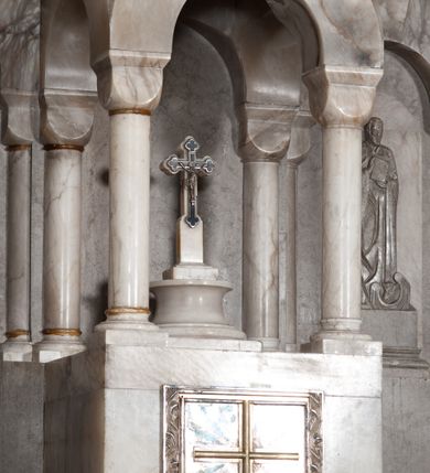 Zdjęcie nr 13: Ołtarz przyścienny, architektoniczny, pięcioosiowy, dwukondygnacyjny ze zwieńczeniem. Mensa kamienna, w formie stołu wsparta na parach kolumn o kostkowych kapitelach. Antepedium również kamienne, z umieszczonym w centrum monogramem IHS zwieńczonym krzyżem. Kondygnacja pierwsza artykułowana pięcioma arkadami ujętymi kolumienkami o kostkowych kapitelach. W arkadach umieszczone płaskorzeźbione postaci czterech ewangelistów: Jana, Marka, Łukasza i Mateusza. W osi środkowej prostopadłościenne, alabastrowe tabernakulum z tronem wystawienia nakrytym kamiennym baldachimem w formie kopuły wspartej na czterech kolumnach o kostkowych kapitelach. Na drzwiczkach umieszczony krzyż na tle glorii promienistej flankowany przez postaci klęczących aniołów. Kondygnacja druga artykułowana arkadami wspartymi na kolumnach o kostkowych kapitelach. W arkadach umieszczone dary wotywne. W osi środkowej znajduje się obraz Matki Boskiej z Dzieciątkiem w prostokątnej, złotej ramie. Struktura zwieńczona profilowanym gzymsem, ponad którym umieszczono płaskorzeźbione przedstawienie Baranka Apokaliptycznego ujętego medalionem zwieńczonym krzyżem oraz flankowanego przez postaci dwóch klęczących aniołów.
