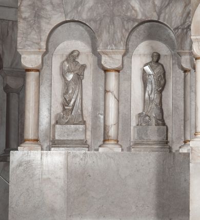 Zdjęcie nr 14: Ołtarz przyścienny, architektoniczny, pięcioosiowy, dwukondygnacyjny ze zwieńczeniem. Mensa kamienna, w formie stołu wsparta na parach kolumn o kostkowych kapitelach. Antepedium również kamienne, z umieszczonym w centrum monogramem IHS zwieńczonym krzyżem. Kondygnacja pierwsza artykułowana pięcioma arkadami ujętymi kolumienkami o kostkowych kapitelach. W arkadach umieszczone płaskorzeźbione postaci czterech ewangelistów: Jana, Marka, Łukasza i Mateusza. W osi środkowej prostopadłościenne, alabastrowe tabernakulum z tronem wystawienia nakrytym kamiennym baldachimem w formie kopuły wspartej na czterech kolumnach o kostkowych kapitelach. Na drzwiczkach umieszczony krzyż na tle glorii promienistej flankowany przez postaci klęczących aniołów. Kondygnacja druga artykułowana arkadami wspartymi na kolumnach o kostkowych kapitelach. W arkadach umieszczone dary wotywne. W osi środkowej znajduje się obraz Matki Boskiej z Dzieciątkiem w prostokątnej, złotej ramie. Struktura zwieńczona profilowanym gzymsem, ponad którym umieszczono płaskorzeźbione przedstawienie Baranka Apokaliptycznego ujętego medalionem zwieńczonym krzyżem oraz flankowanego przez postaci dwóch klęczących aniołów.

